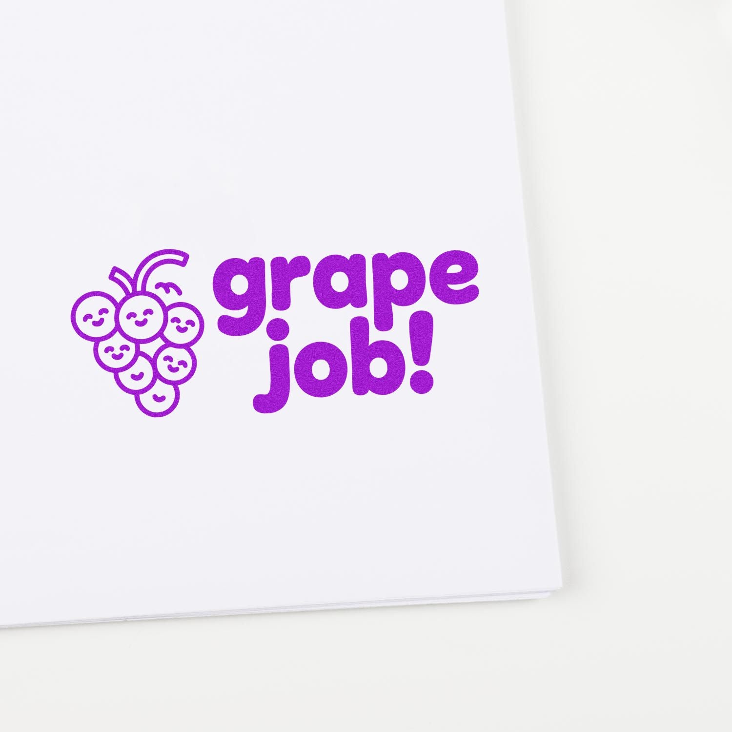 Purple grape job rubber stamp seal with smiling grape cluster logo on white paper
