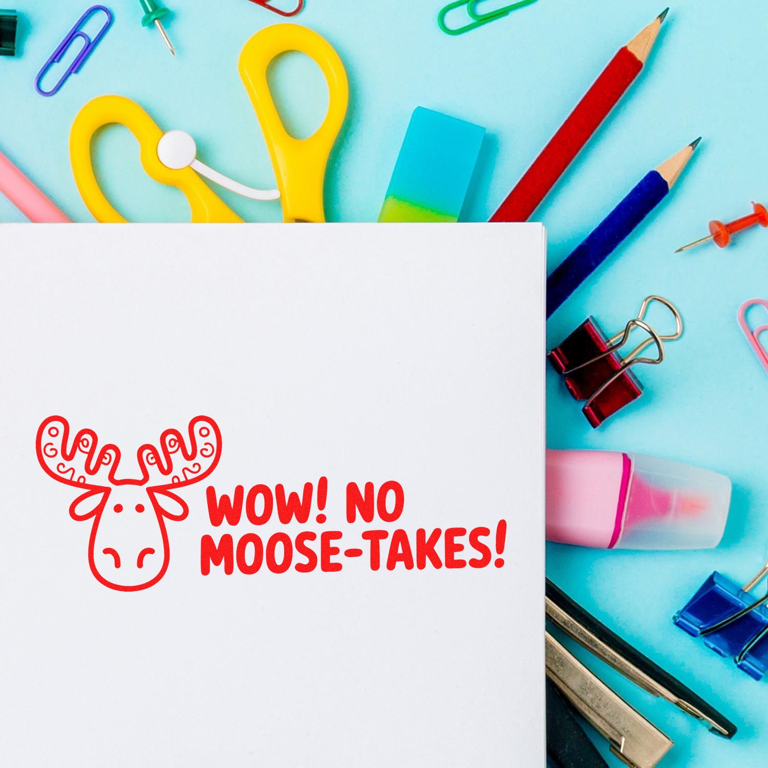 Red moose stamp and seal on white card, surrounded by colorful stationery on a blue background.