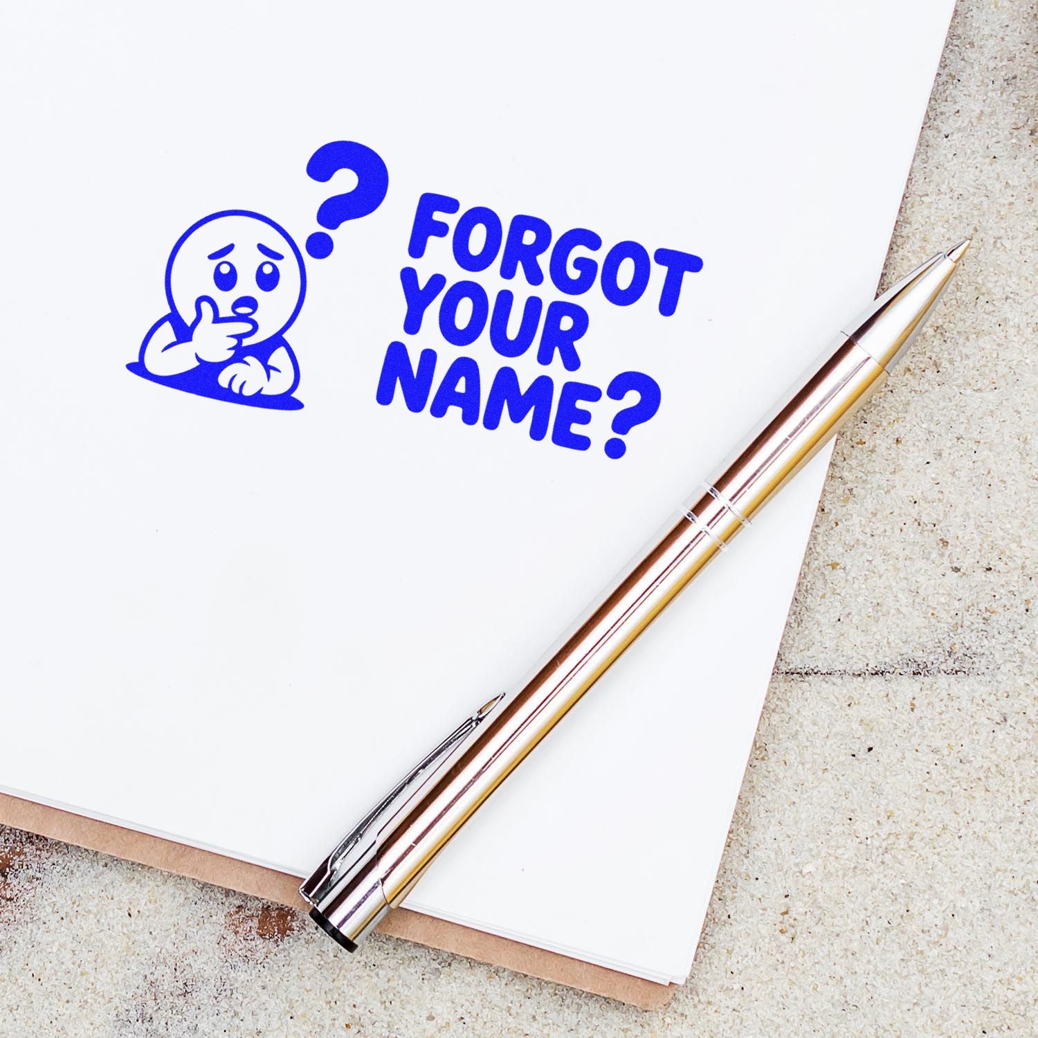 Blue custom stamp reading Forgot your name? with a worried character and question mark, beside a gold-silver pen on white paper.