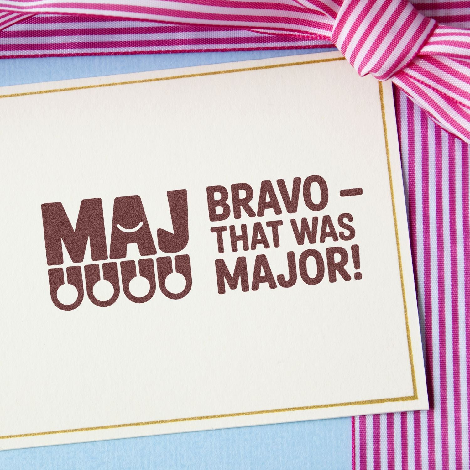 Brown MAJ Bravo That Was Major stamp on cream card with gold border and pink striped ribbon.