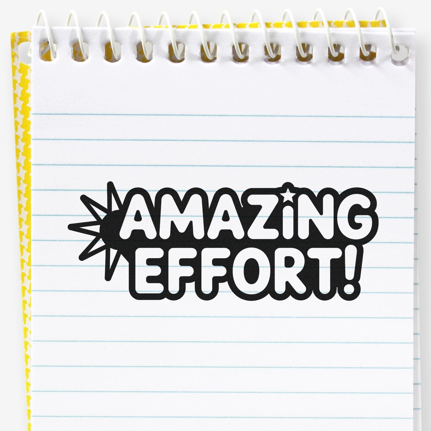 Black AMAZING EFFORT! stamp seal on white spiral notebook page with blue lines and yellow patterned edge.