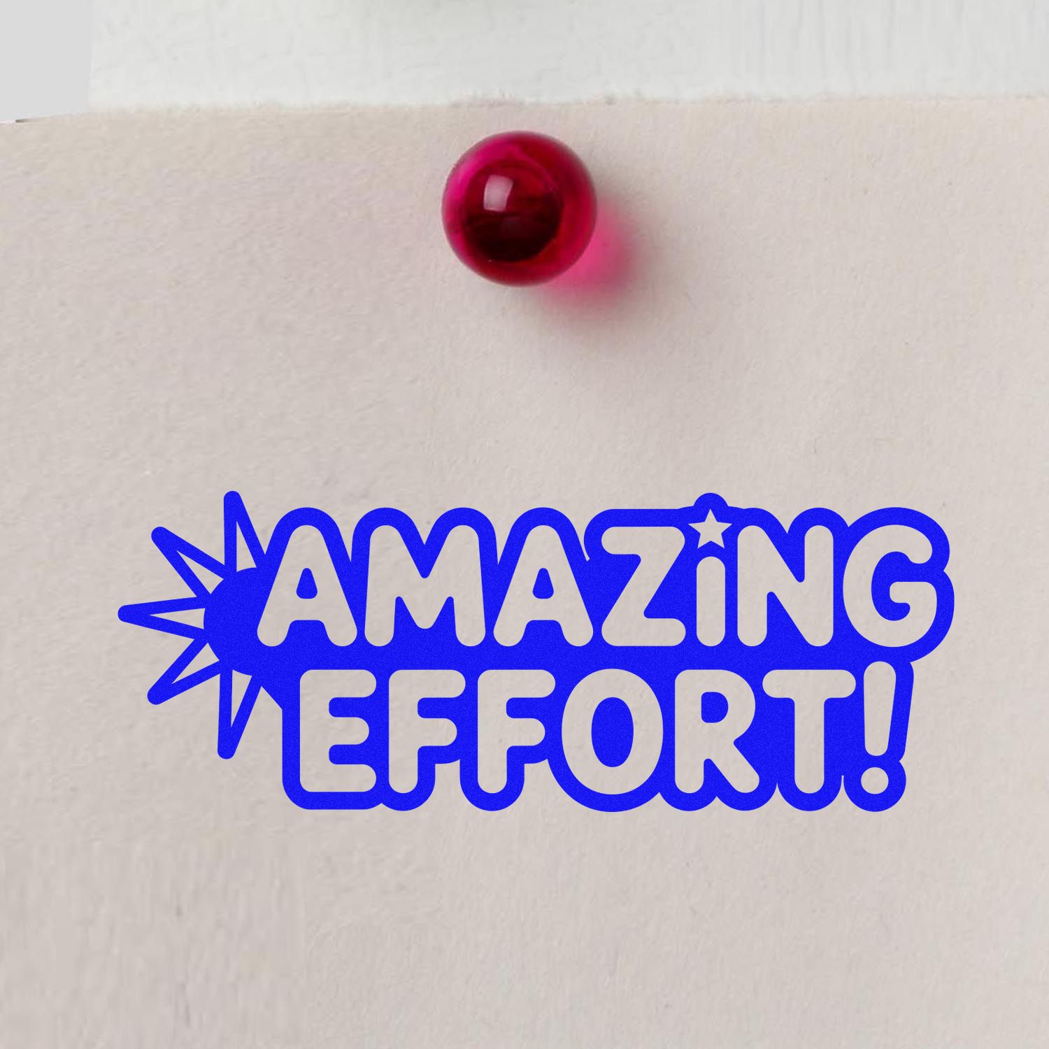 Blue AMAZING EFFORT! stamp on white paper with a red seal-like pushpin accent.