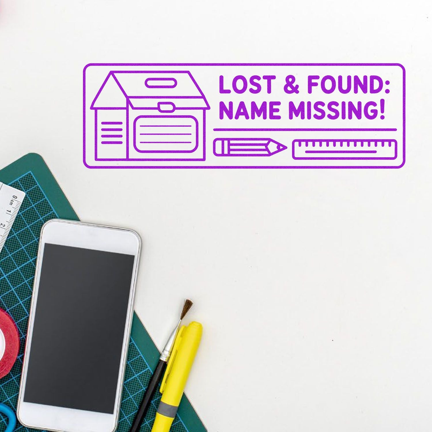 Purple self-inking stamp seal reading Lost & Found: Name Missing! with box, pencil and ruler icons on white desk.