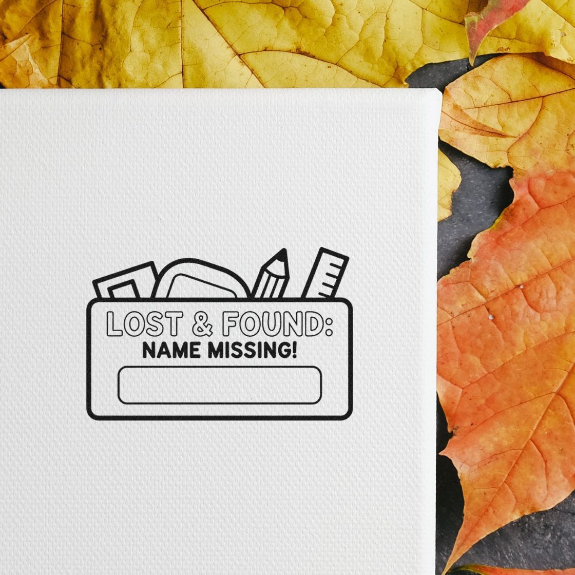 Black Lost & Found Name Missing stamp seal on white textured card, with yellow and orange autumn leaves.