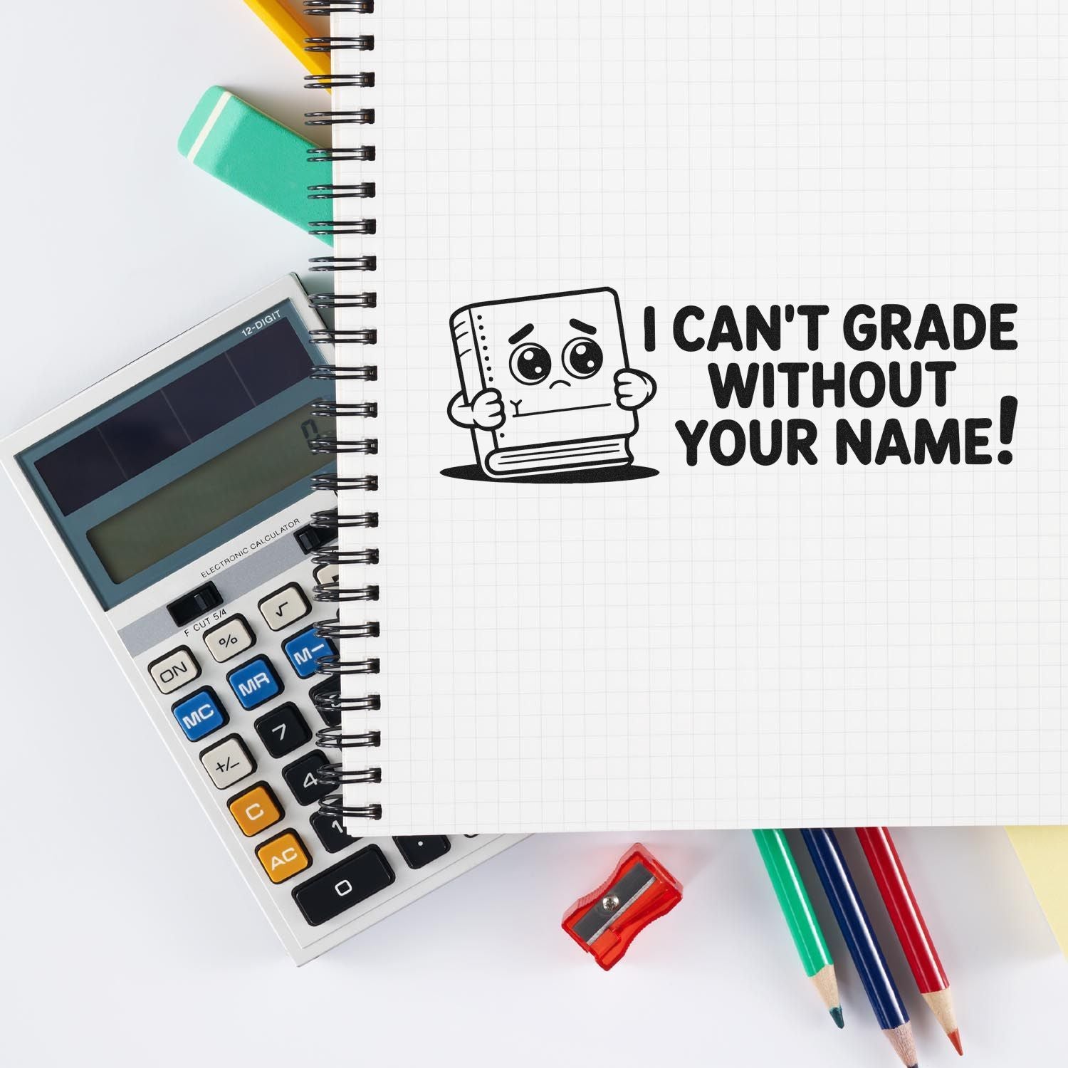 Black custom teacher stamp and seal reading I cant grade without your name! on white notebook with calculator, pencils, and red sharpener.