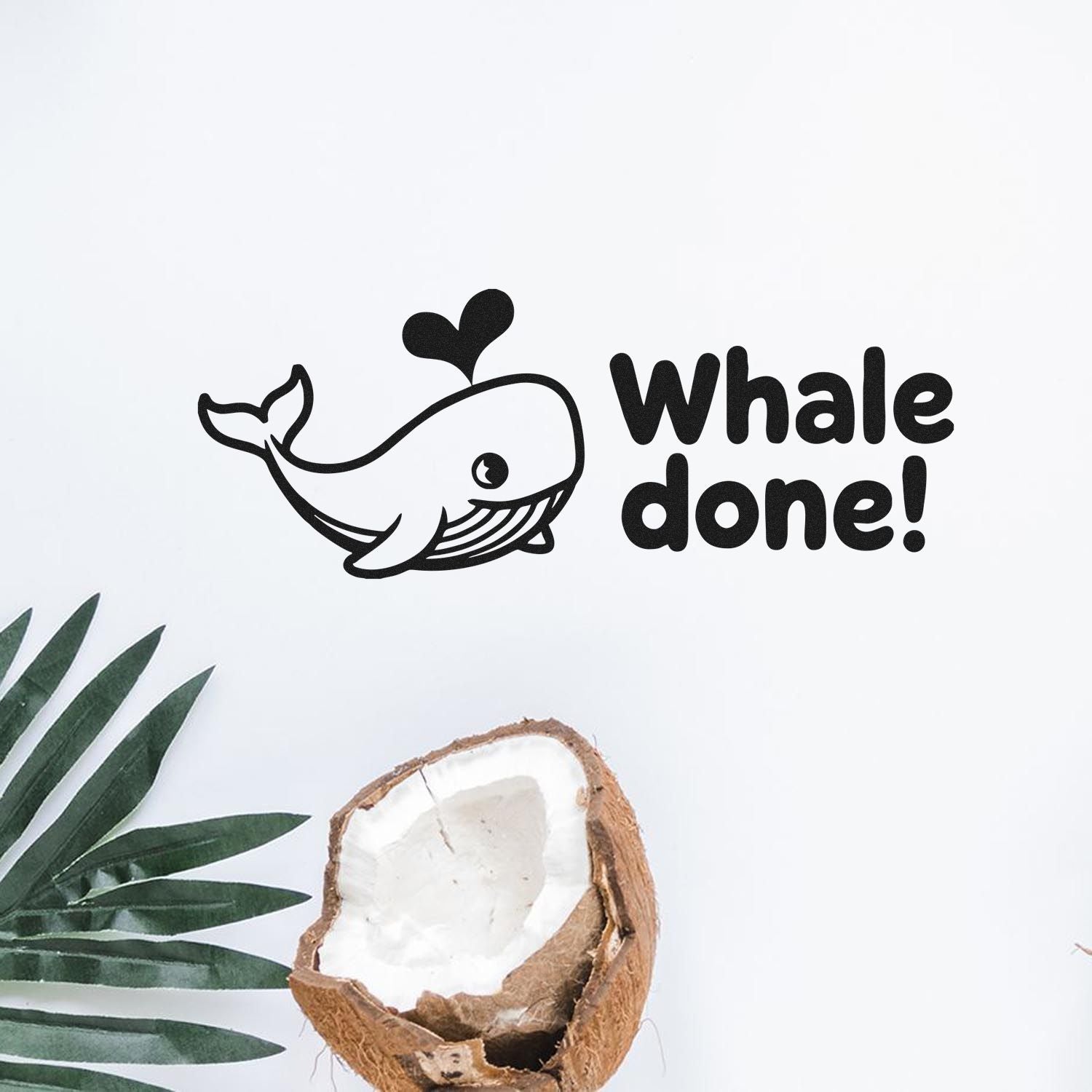 Black whale rubber stamp seal with Whale done! text on white background, accented by green leaves and a coconut shell.