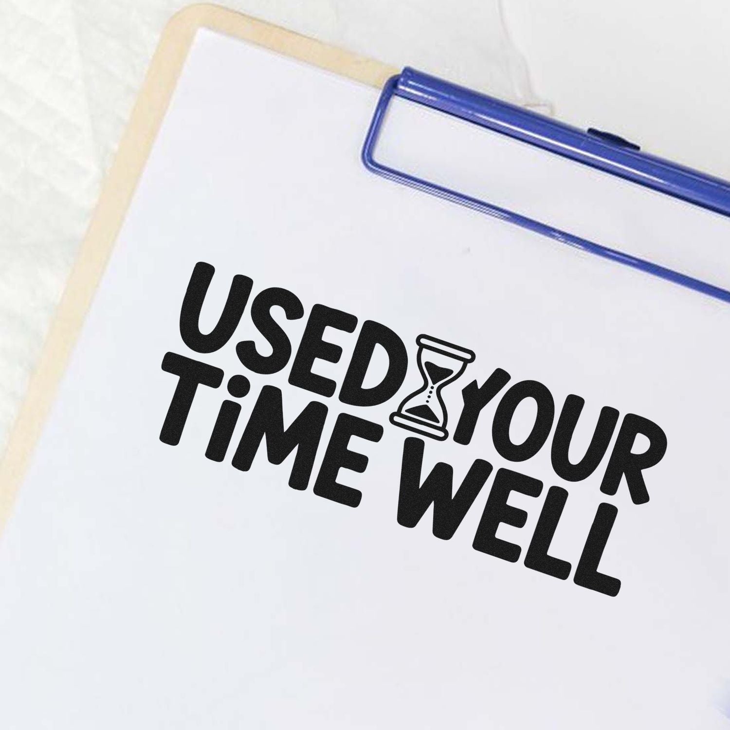 Blue self-inking stamp and beige seal with black USED YOUR TIME WELL text and hourglass on white.