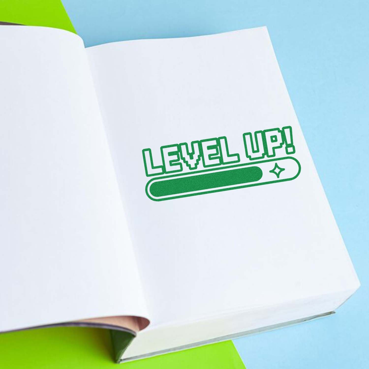 Green LEVEL UP stamp seal on an open white notebook, with blue background and lime green accents.