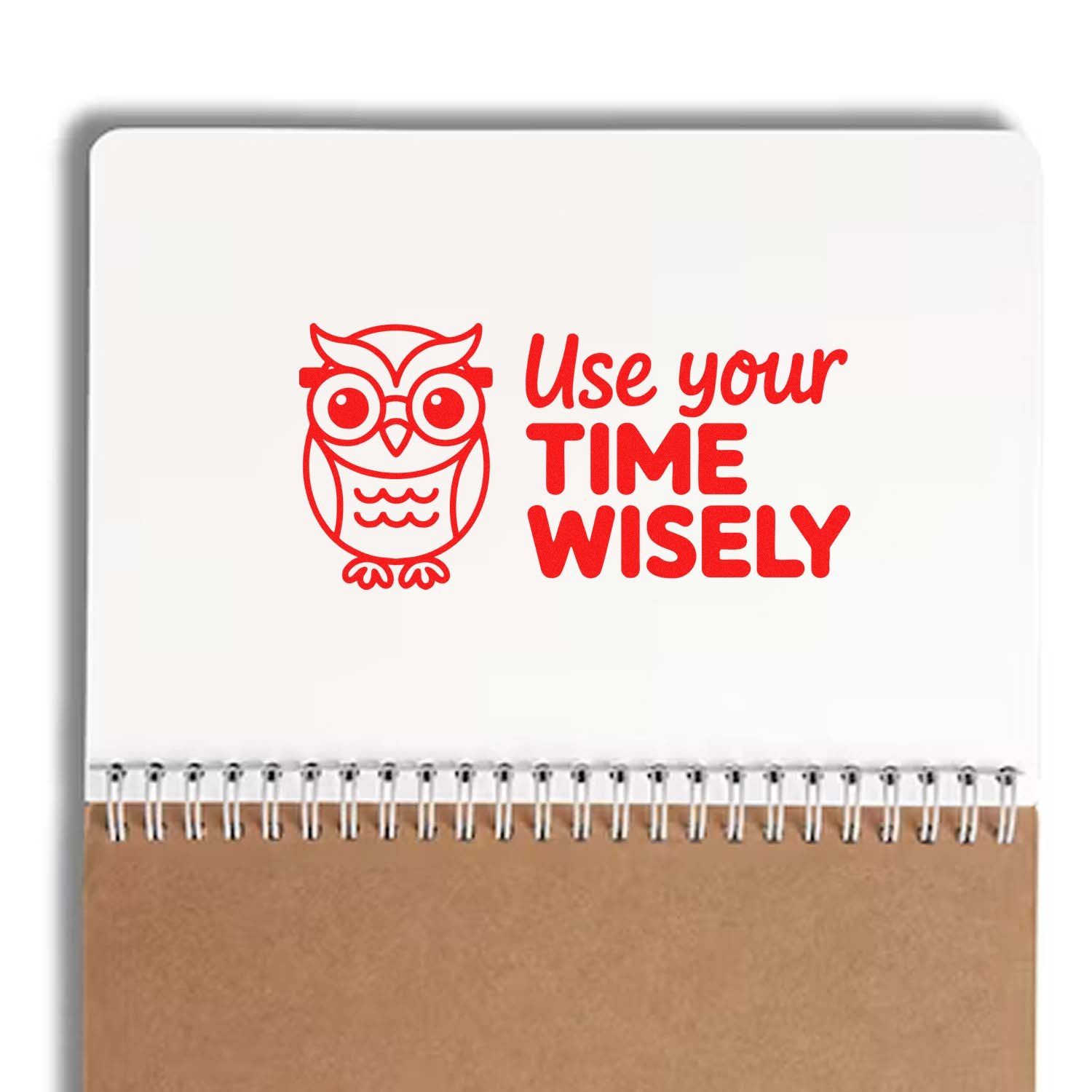 Red owl rubber stamp with Use your time wisely on white spiral notebook above kraft paper.