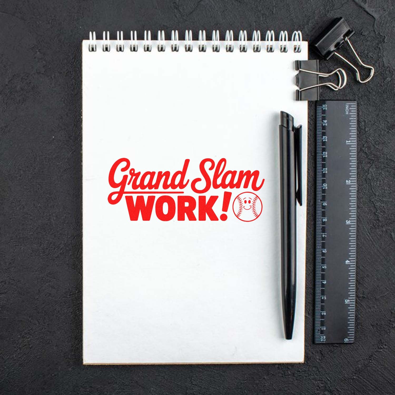 White spiral notebook with red Grand Slam WORK! baseball stamp and seal, plus black pen, ruler and binder clips.