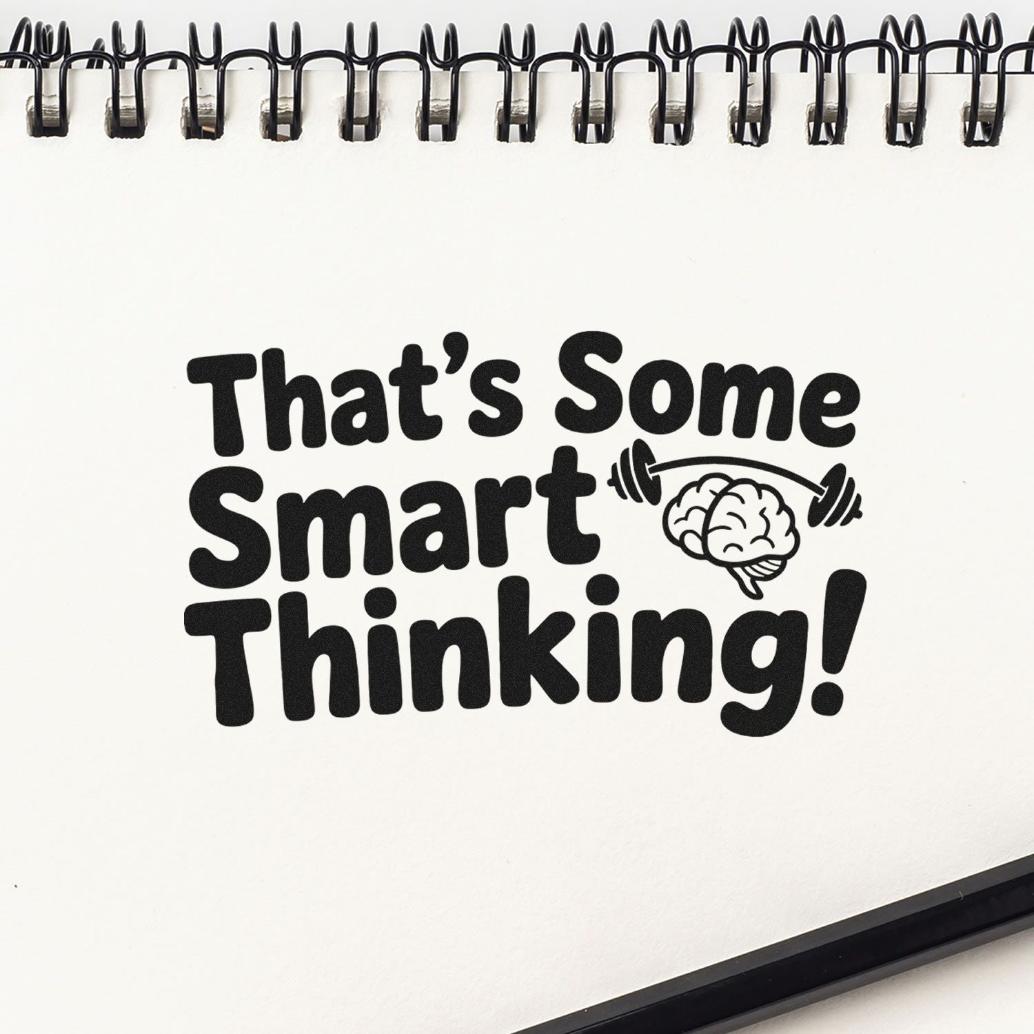 Black stamp/seal reading Thats Some Smart Thinking! with brain and dumbbell on a white spiral notebook page.
