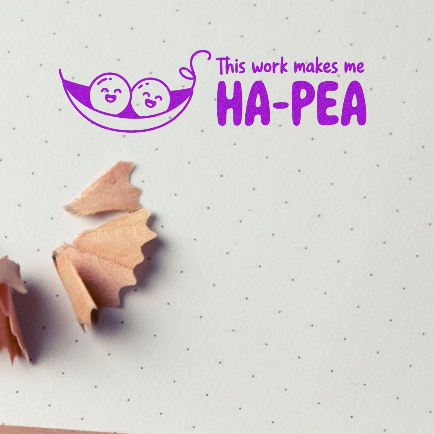 Purple stamp and seal with smiling pea pod and This work makes me HA-PEA on dotted paper, with pencil shavings.