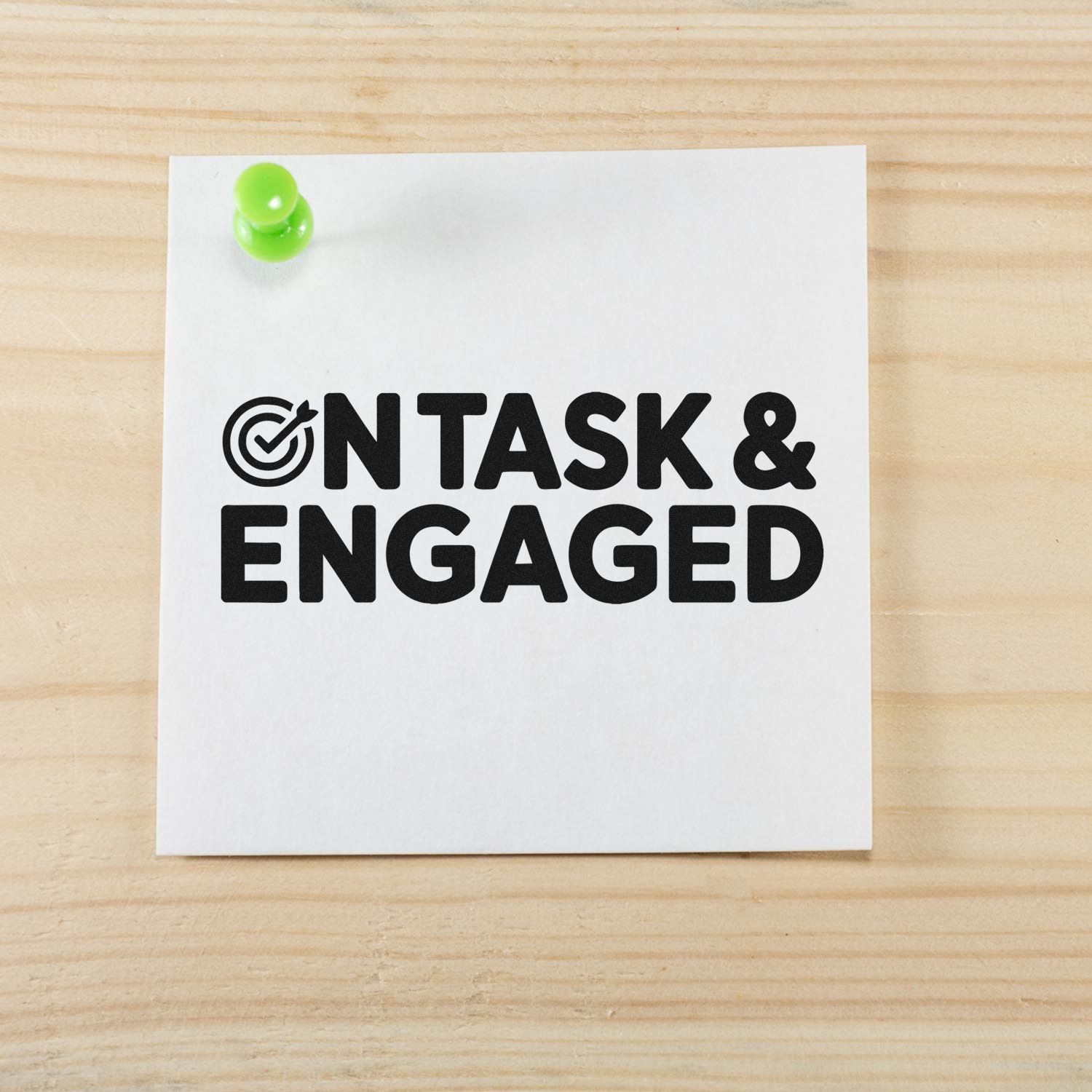 White stamp-and-seal card with black ONTASK & ENGAGED text, target icon, and green pushpin on light wood.