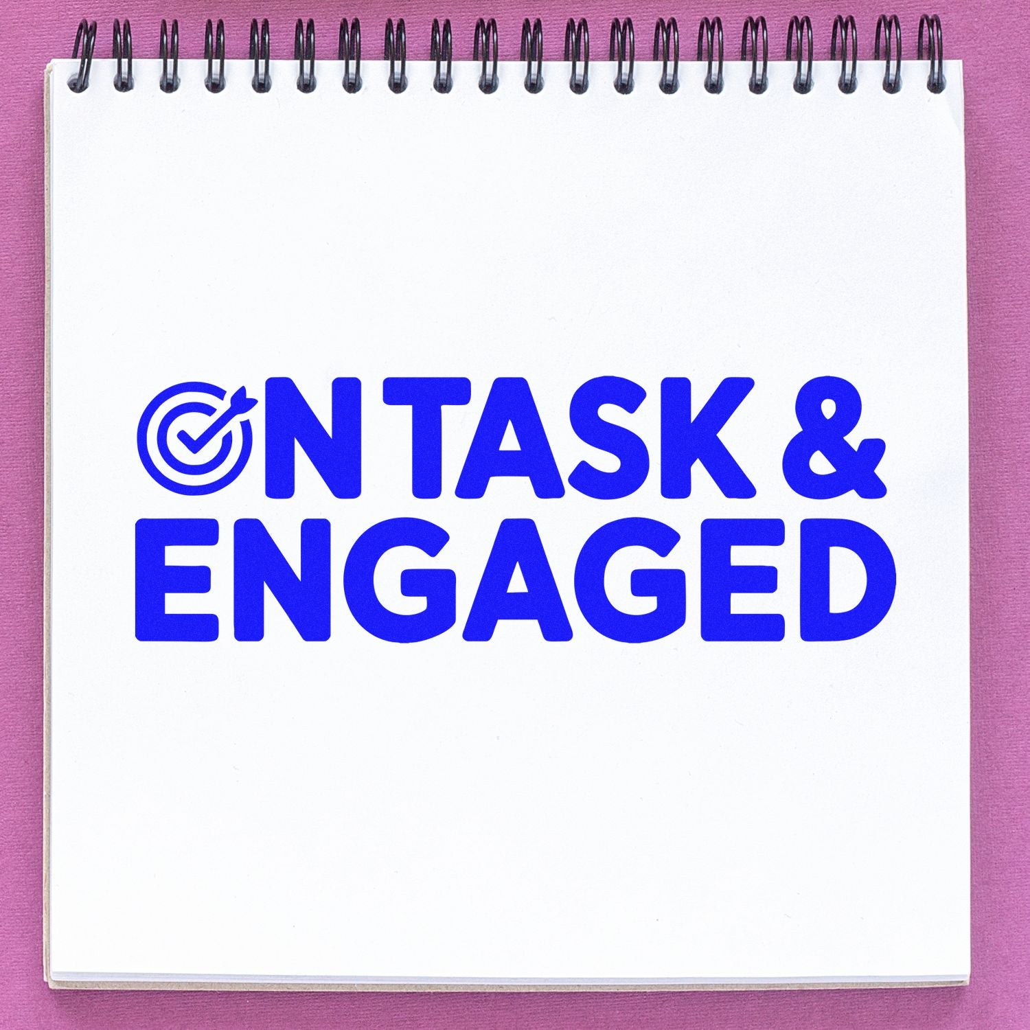 Blue ON TASK & ENGAGED stamp and seal in bright blue on a white spiral notebook, with target checkmark and pink background.