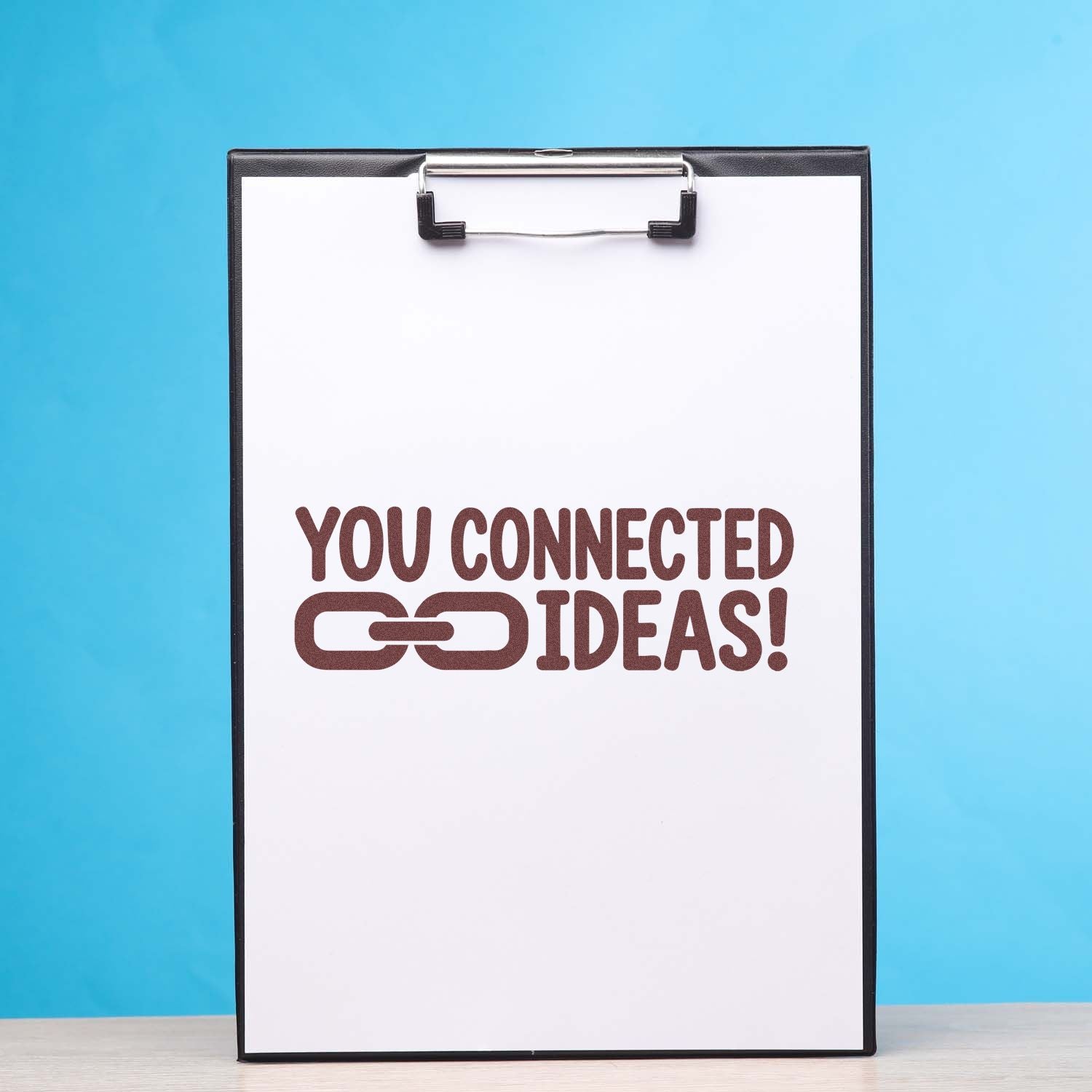 Custom stamp and seal on white clipboard reads You Connected Ideas! in brown on a blue background.