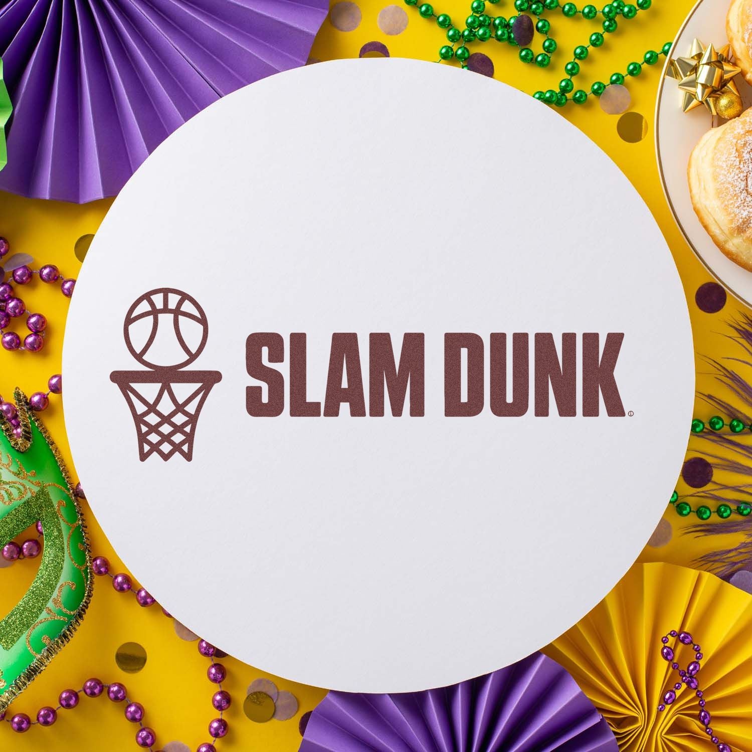 Basketball Slam Dunk stamp and seal on white circle, surrounded by purple, green and gold Mardi Gras decorations.