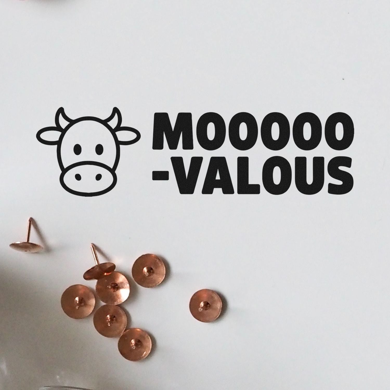 Black MOOO-VALOUS cow logo with copper stamp and seal discs on a white background