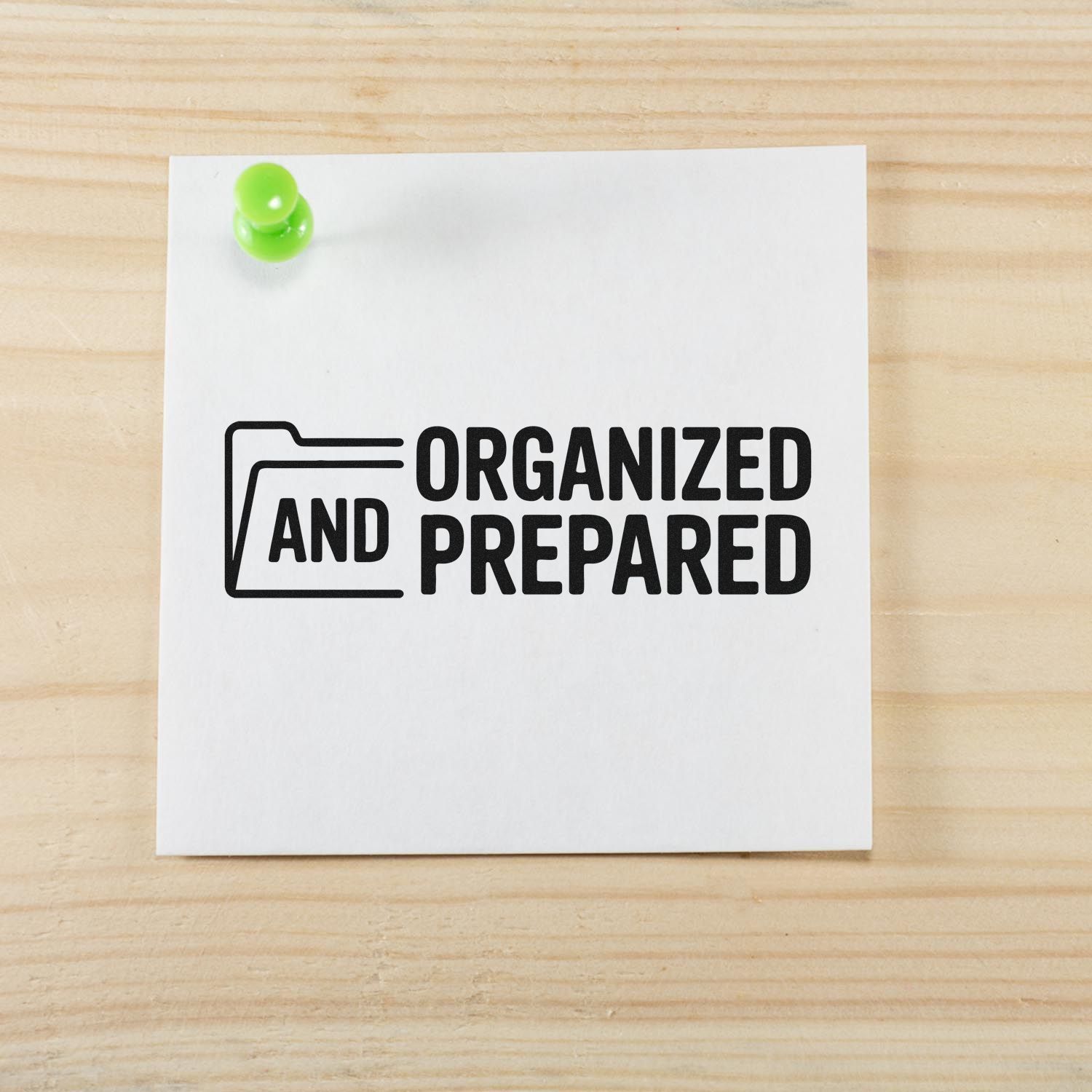 Black stamp reading ORGANIZED AND PREPARED with folder icon on white card, pinned by a lime green tack on wood surface