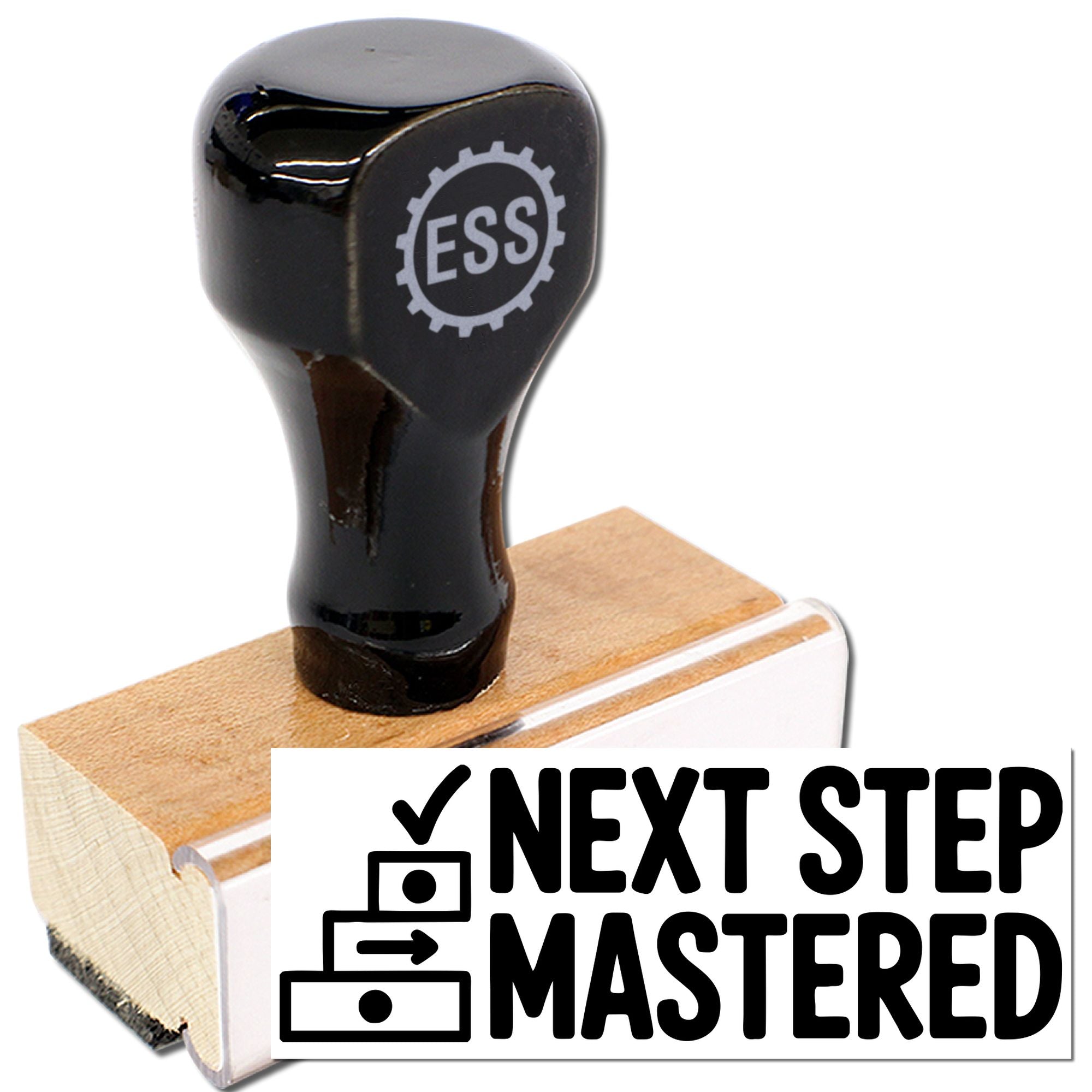 Black ESS self-inking stamp on a wooden mount, creating a bold NEXT STEP MASTERED seal in black.