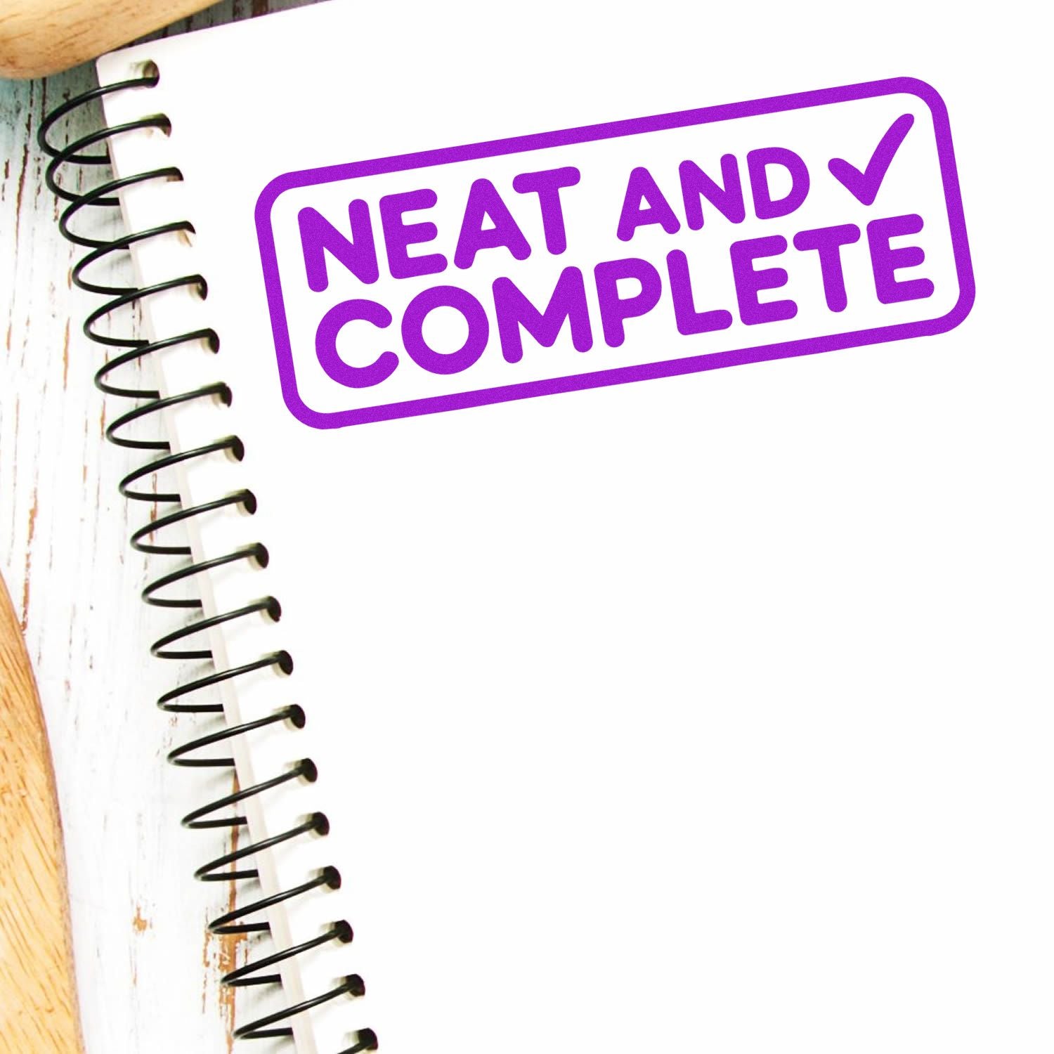 Purple Neat and Complete stamp seal on a spiral notebook, with bold violet text and a white background.