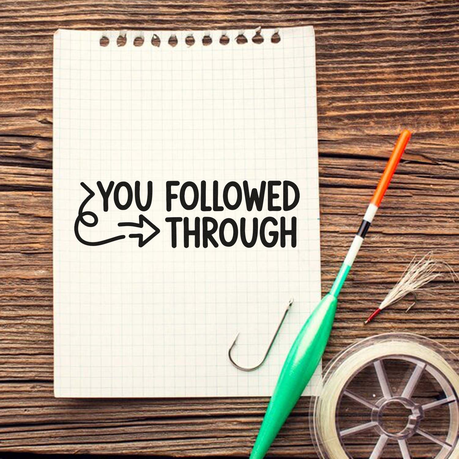Black You followed through stamp, green fishing lure, orange pen, and clear seal tape on a grid notepad.