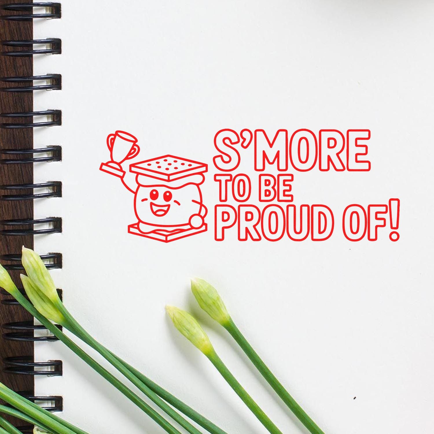 Red stamp seal with trophy s'more mascot and SMORE TO BE PROUD OF! on a white notebook page.