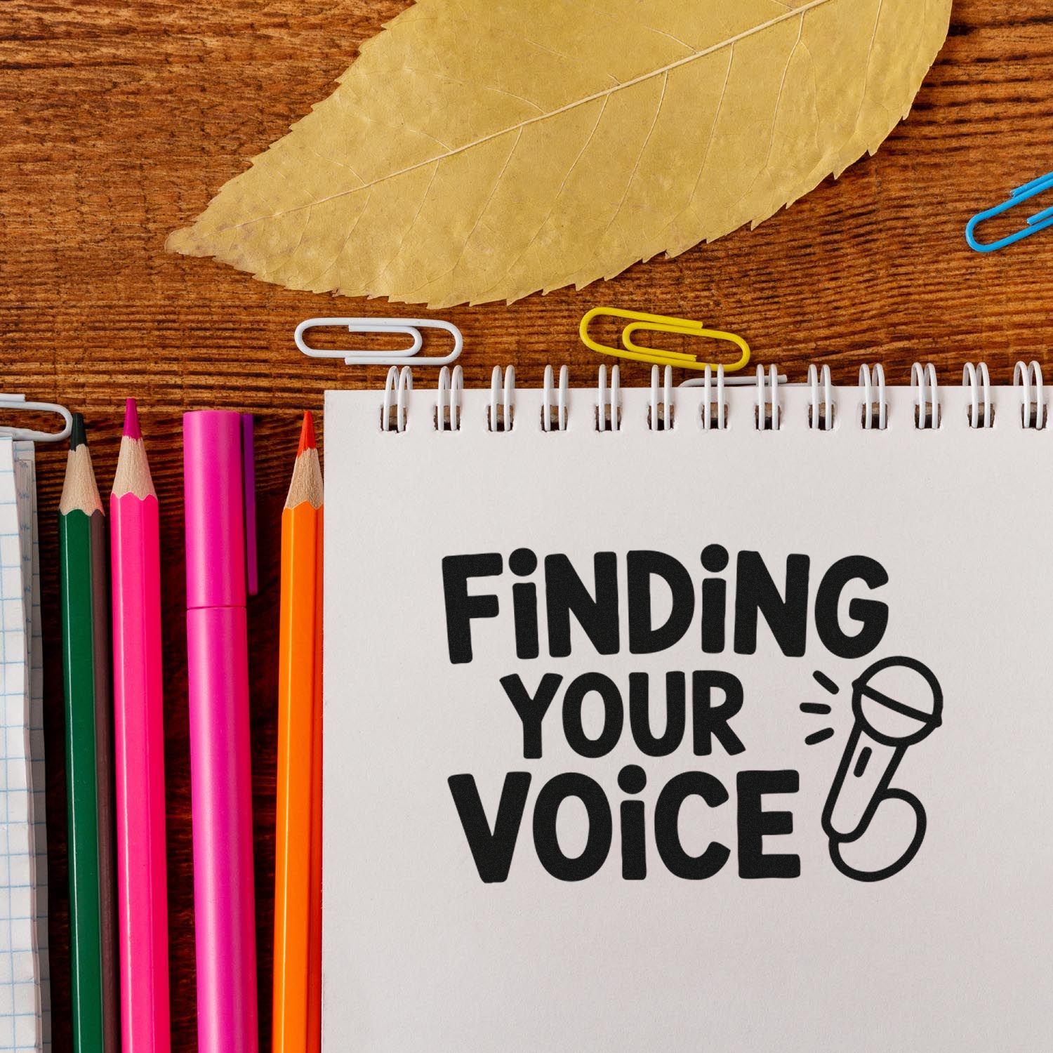 Custom stamp and seal branding notebook with Finding Your Voice text, microphone icon, pencils, and paper clips.