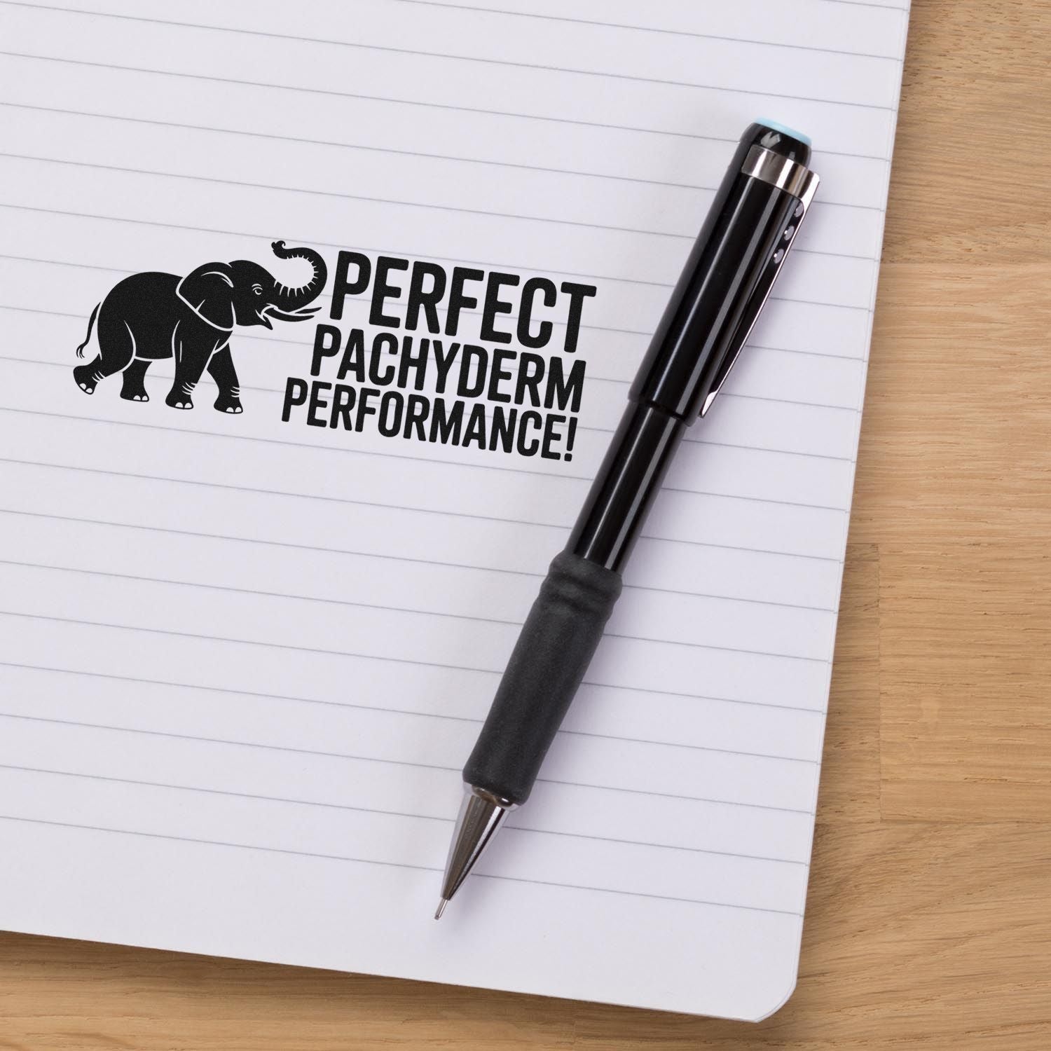 Custom stamp and seal pen with black elephant logo and Perfect Pachyderm Performance! on lined notebook.