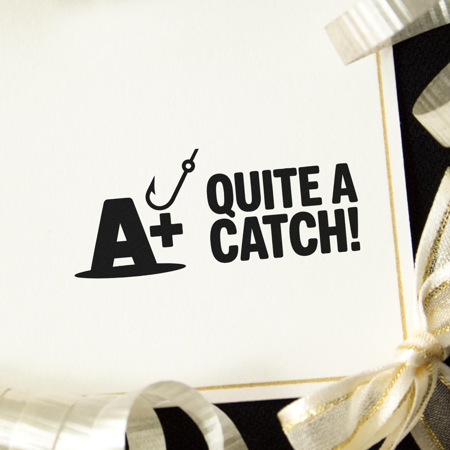 Black fishing-themed stamp and seal reading A+ Quite a Catch! on a white card with gold ribbon trim.