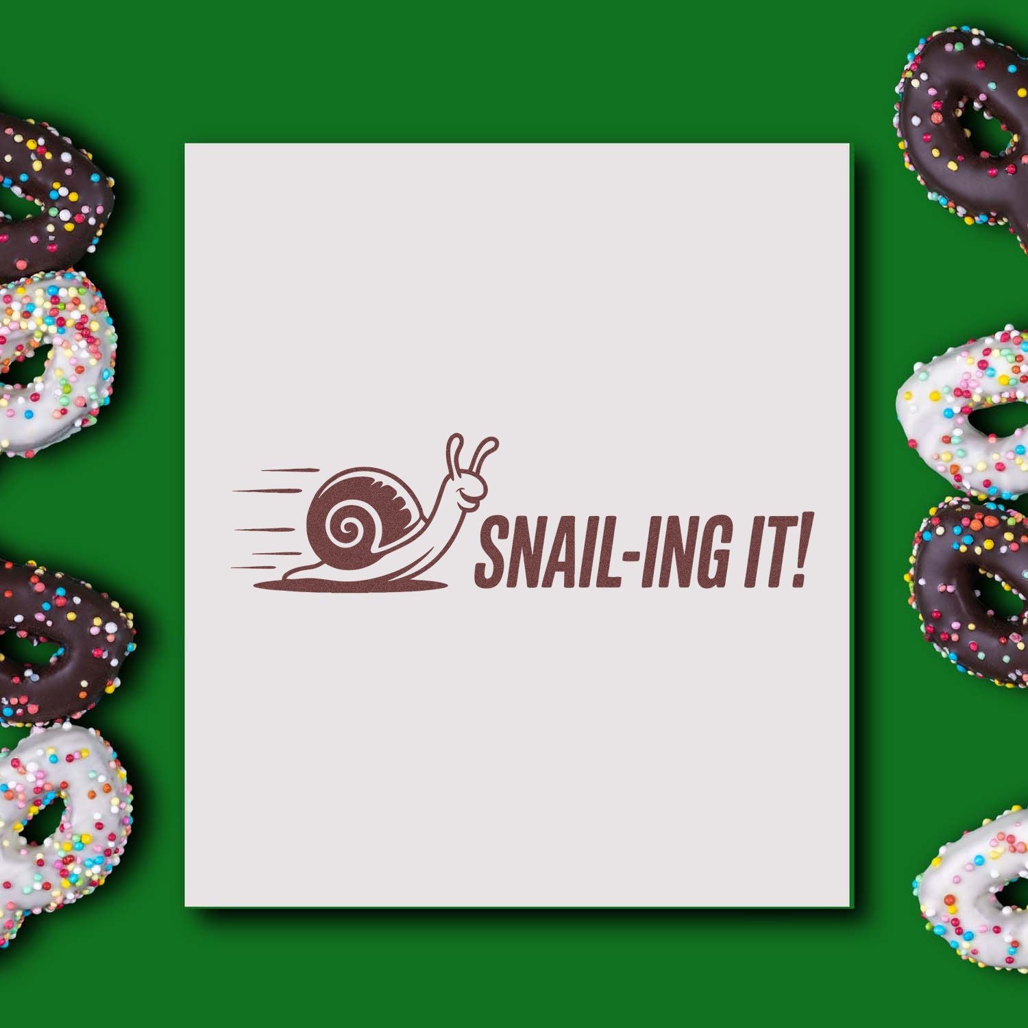 Brown snail stamp and seal reading SNAIL-ING IT! on white card, framed by sprinkle-covered donuts on green background.