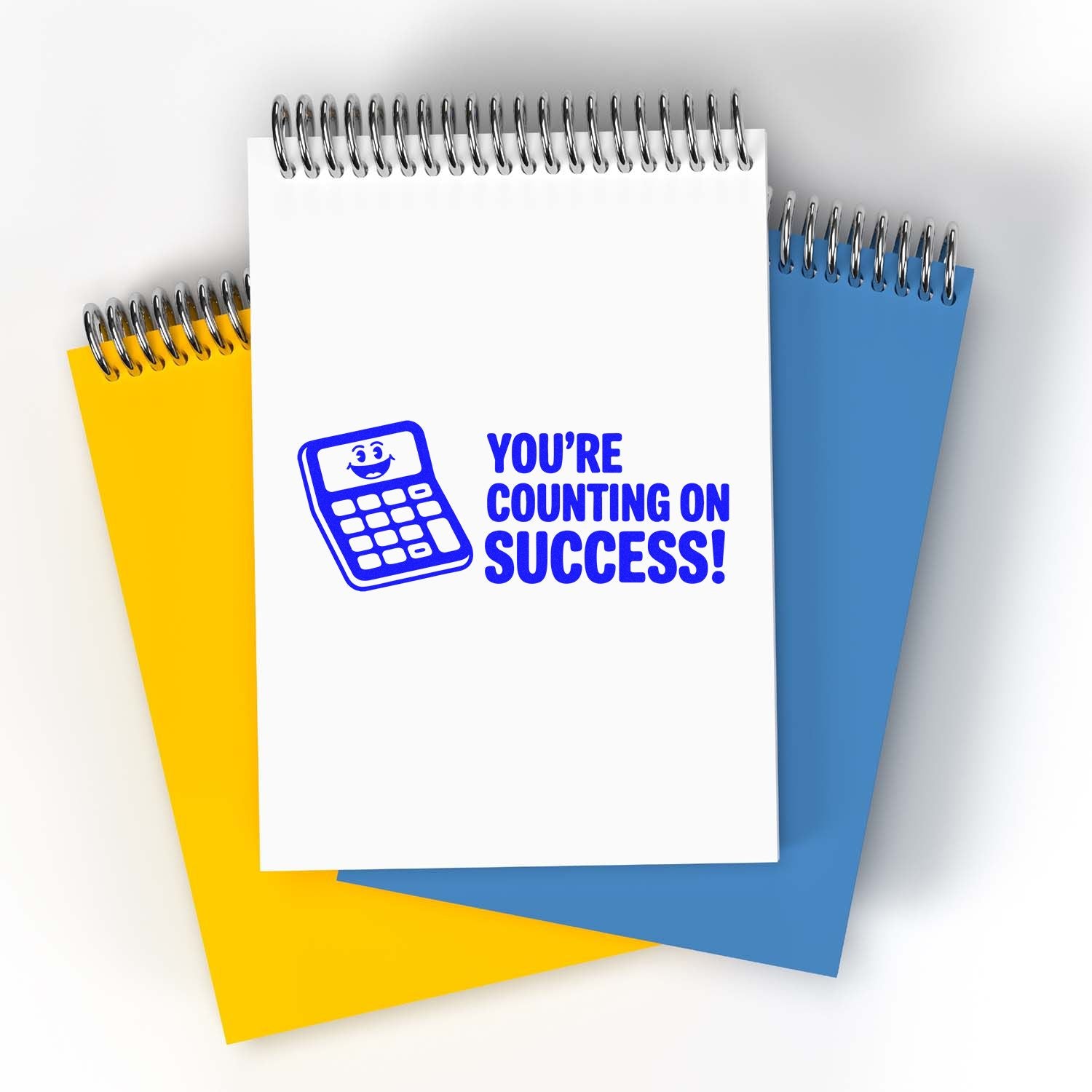 Blue calculator stamp reading Youre Counting on Success! on white spiral notebook with yellow and blue pads