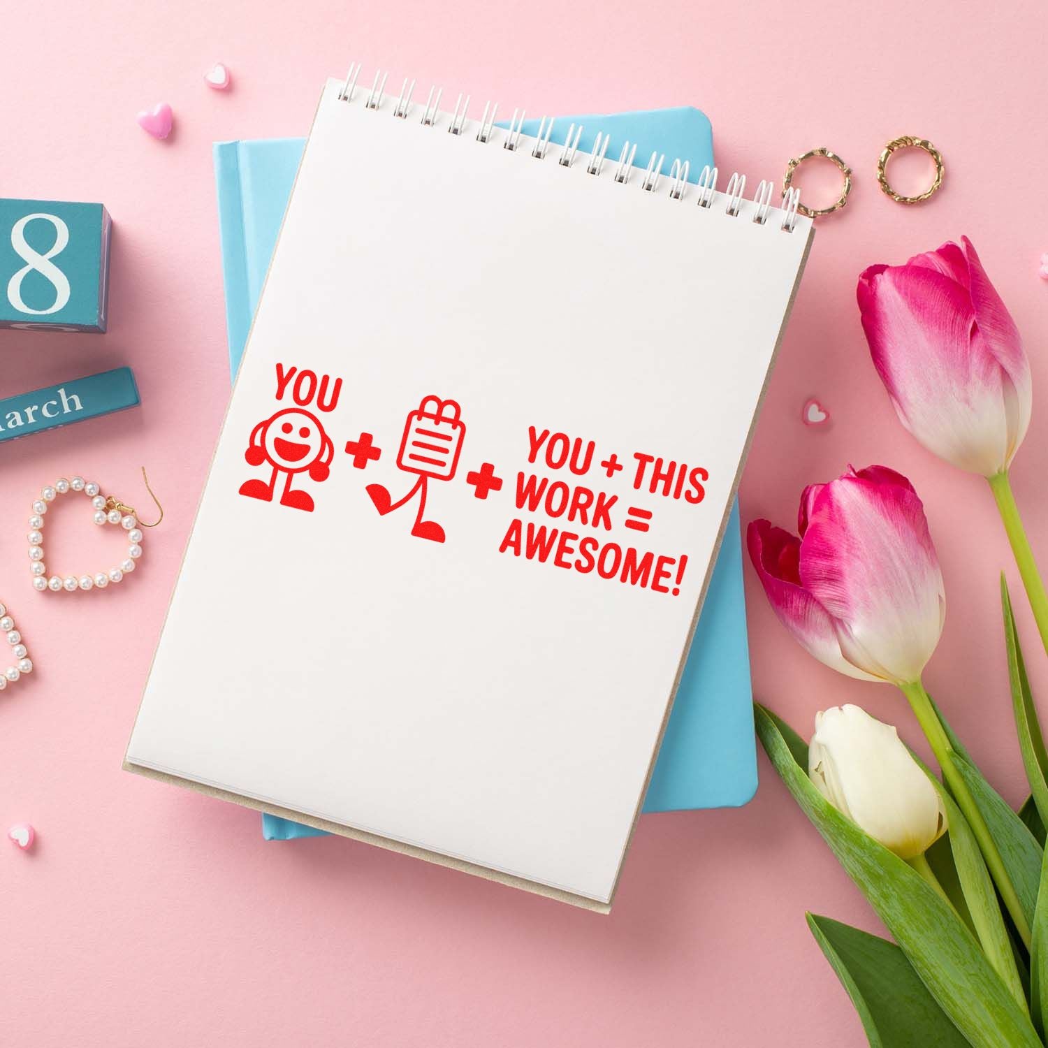 Red rubber stamp reading You + this work = awesome! on a spiral notebook with pink tulips and pastel stationery.