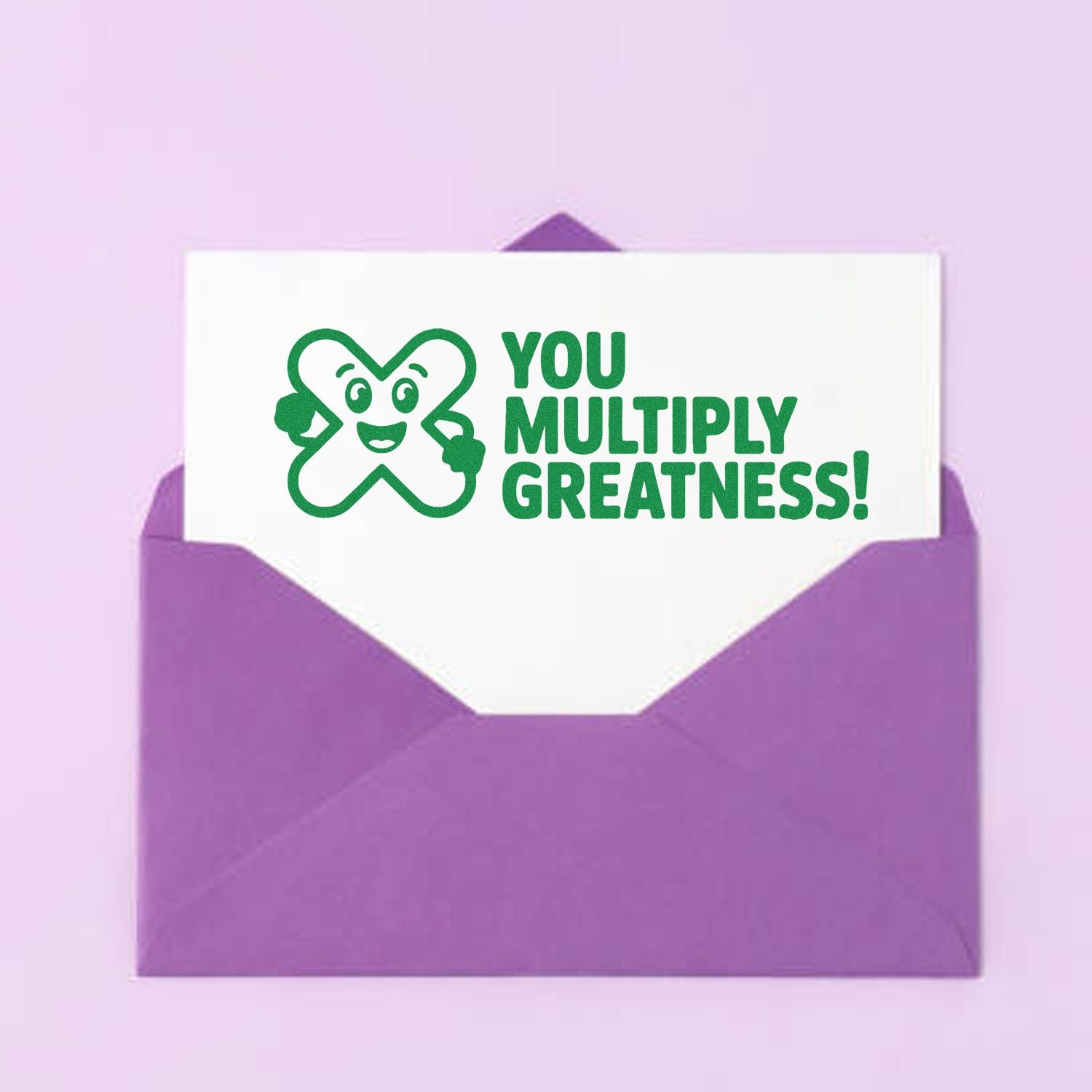 Green stamp seal with smiling clover and You Multiply Greatness! on a white card in a purple envelope.