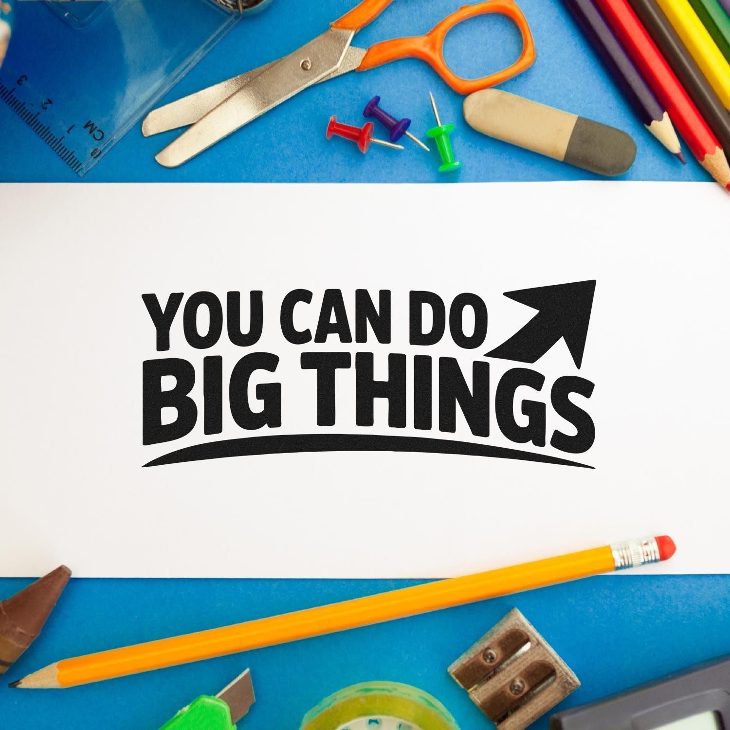 Black "You Can Do Big Things" stamp/seal on white paper, framed by colorful school supplies on a blue background.