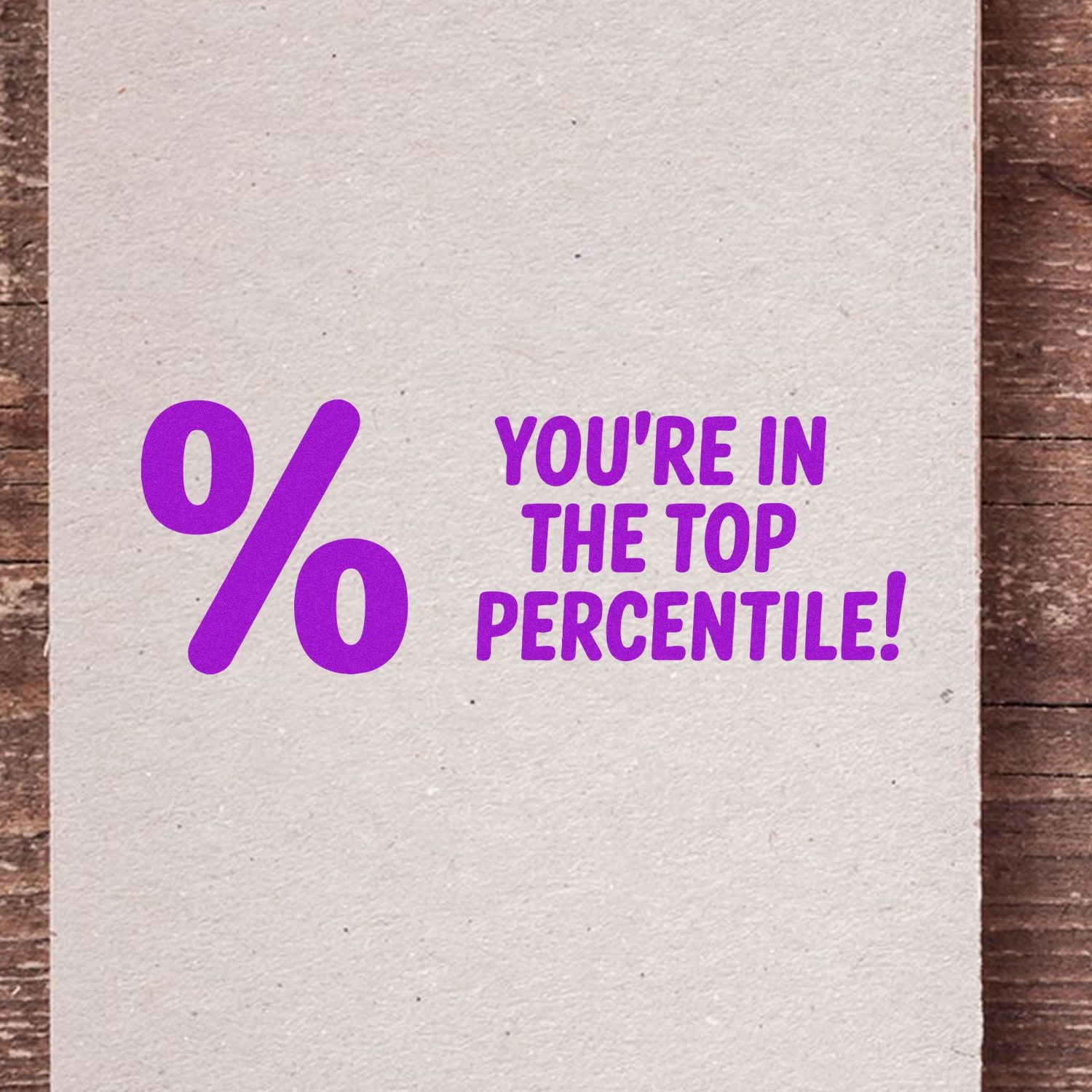 Cream paper stamp with purple seal reading "% Youre in the top percentile!" on rustic wood.