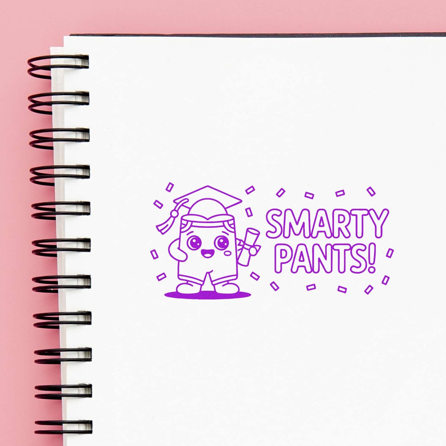 Purple Smarty Pants rubber stamp seal with cute graduate cartoon on a white spiral notebook against pink background.