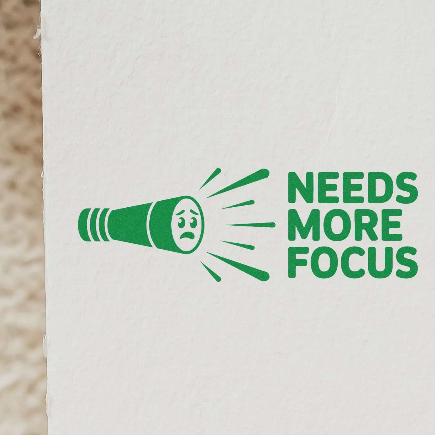Green stamp and seal with sad flashlight icon and bold NEEDS MORE FOCUS text on white paper.