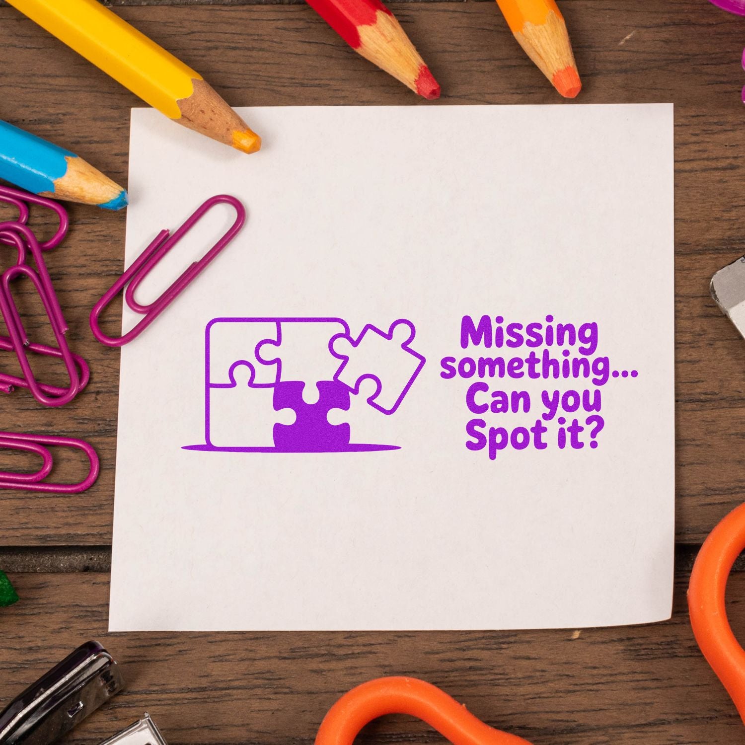 Purple stamp-and-seal puzzle graphic on white paper with Missing something... Can you Spot it? surrounded by colored pencils and paperclips.
