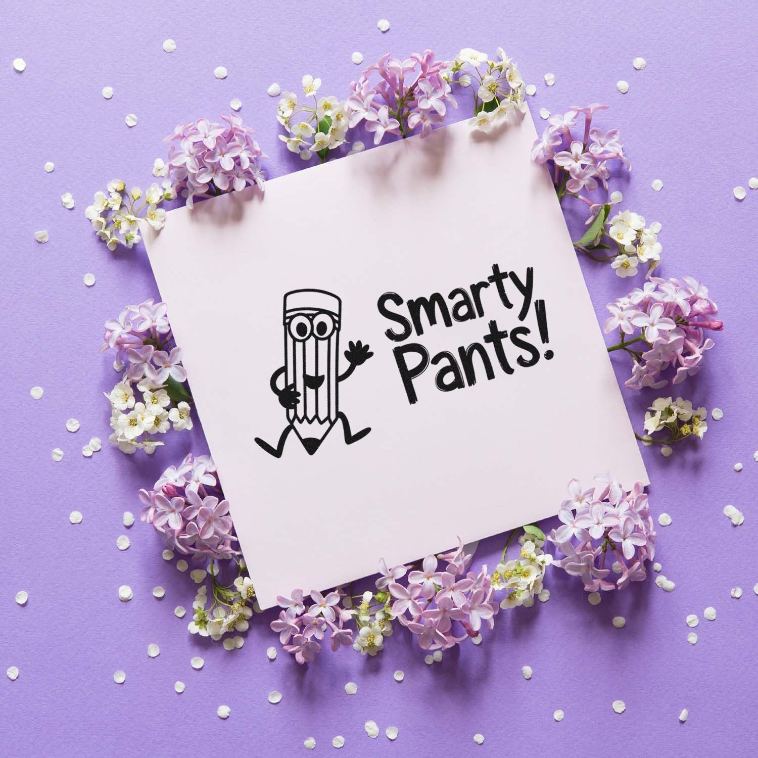 Black Smarty Pants stamp seal on pale pink card, surrounded by lilac flowers and white confetti on a purple background.