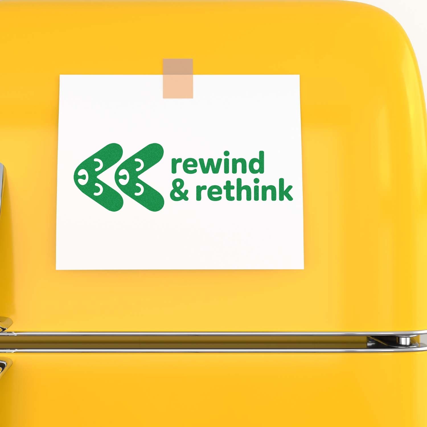 Green rewind & rethink stamp seal on white card, taped to a bright yellow surface.
