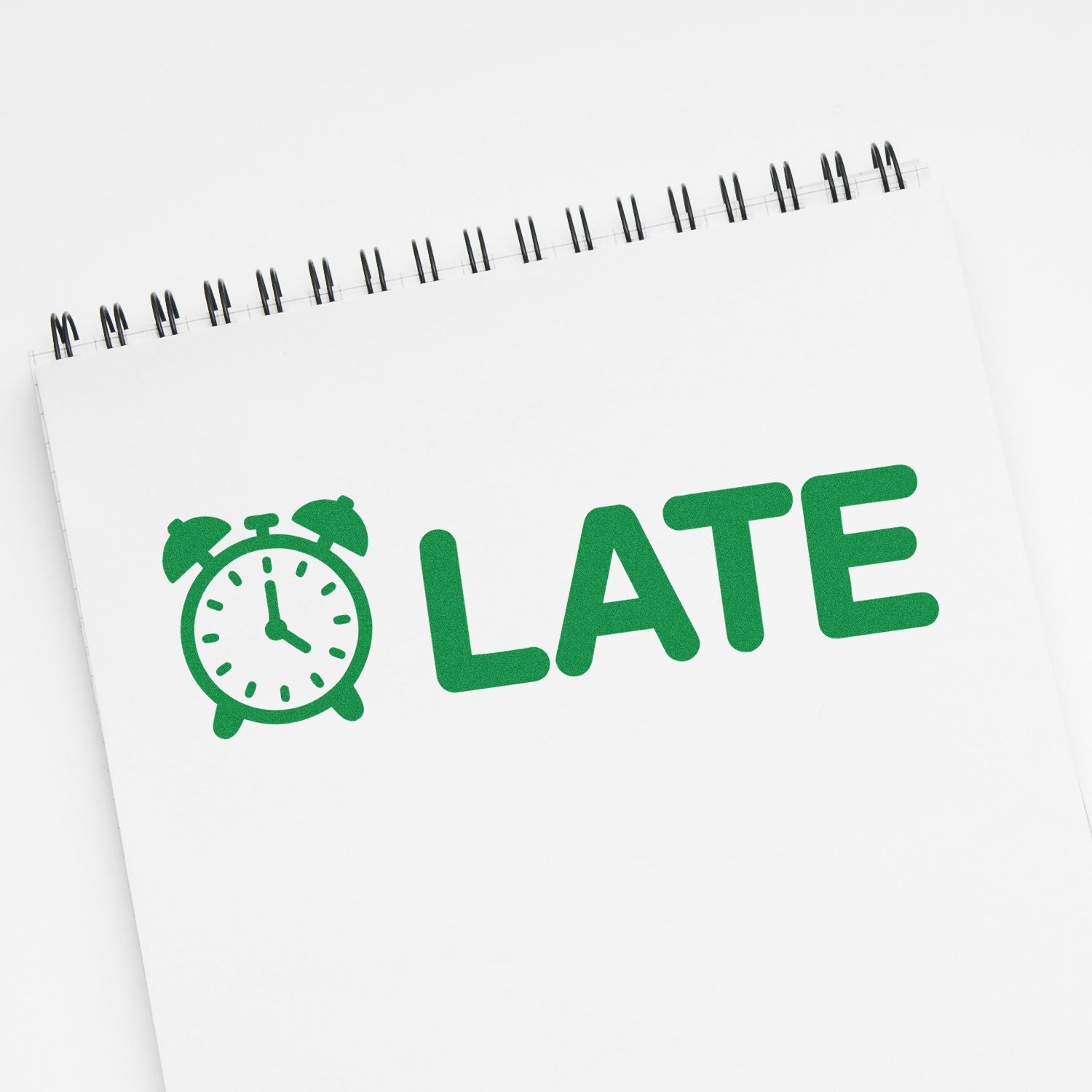 Green LATE stamp seal with alarm clock icon on a white spiral notepad