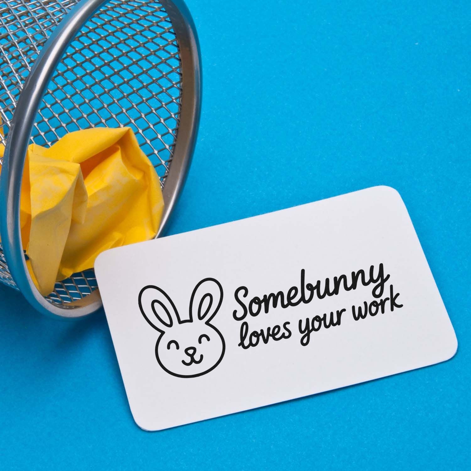 White bunny stamp and seal card with Somebunny loves your work on bright blue background, beside a mesh tray and yellow tissue.