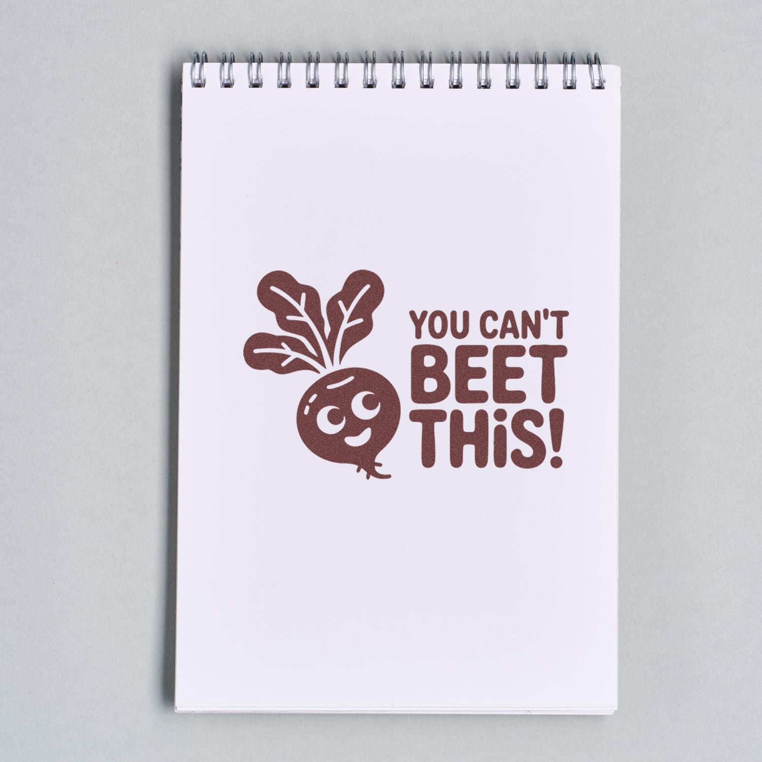 Brown rubber stamp seal on white spiral notepad with beet illustration and text "YOU CAN'T BEET THIS!"