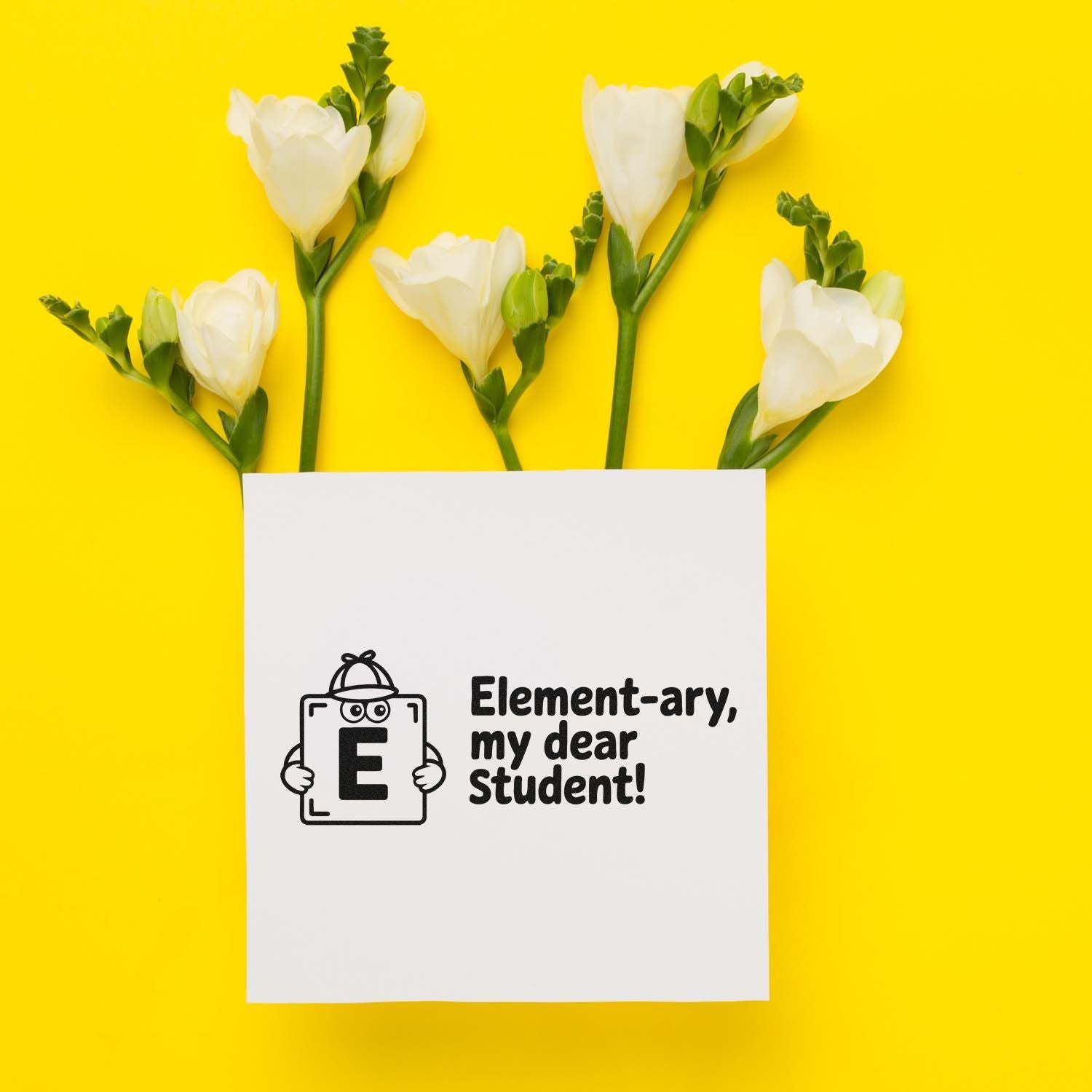 Black stamp/seal design on white card reading Element-ary, my dear Student! with white flowers on a bright yellow background.