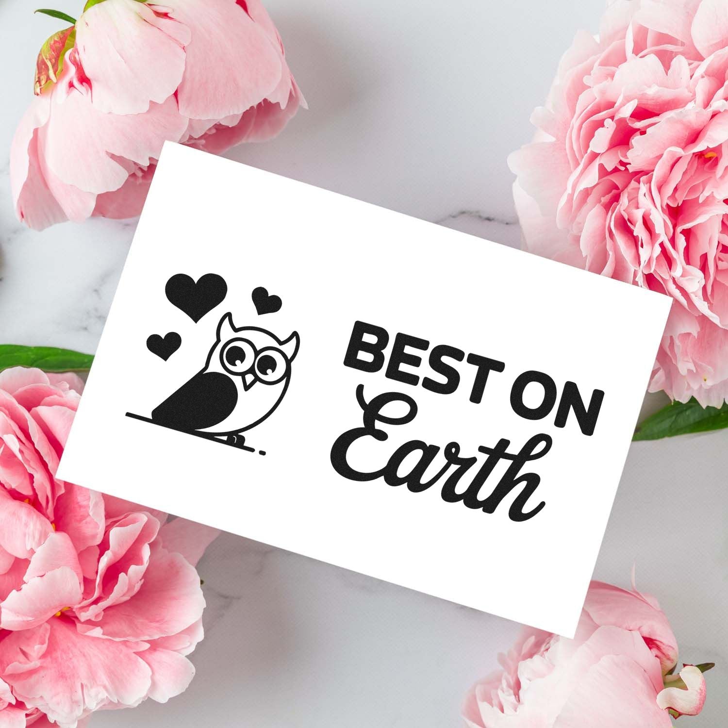 Black owl and hearts stamp seal with BEST ON Earth on white card, framed by pink peonies.