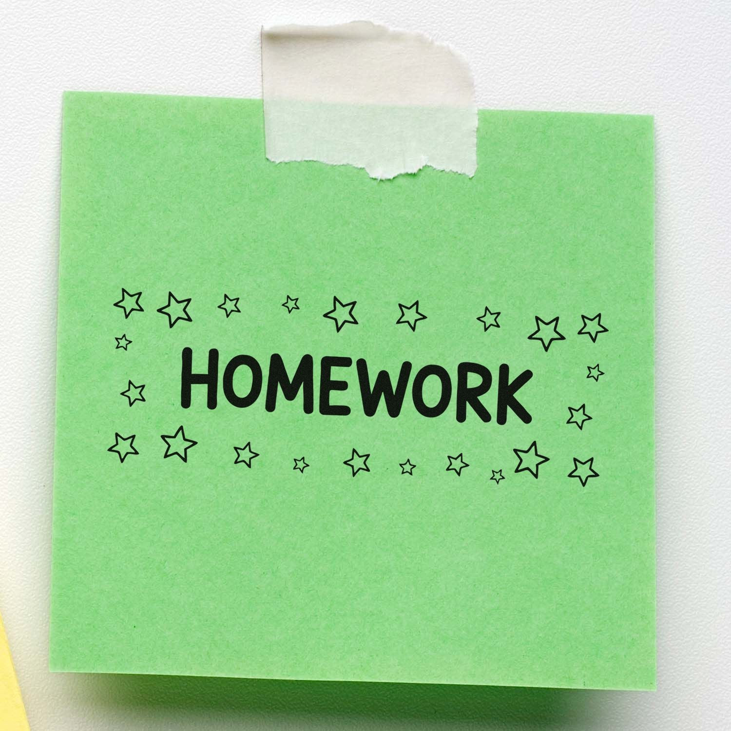 Green homework stamp seal with black stars and bold HOMEWORK text, taped on white paper.