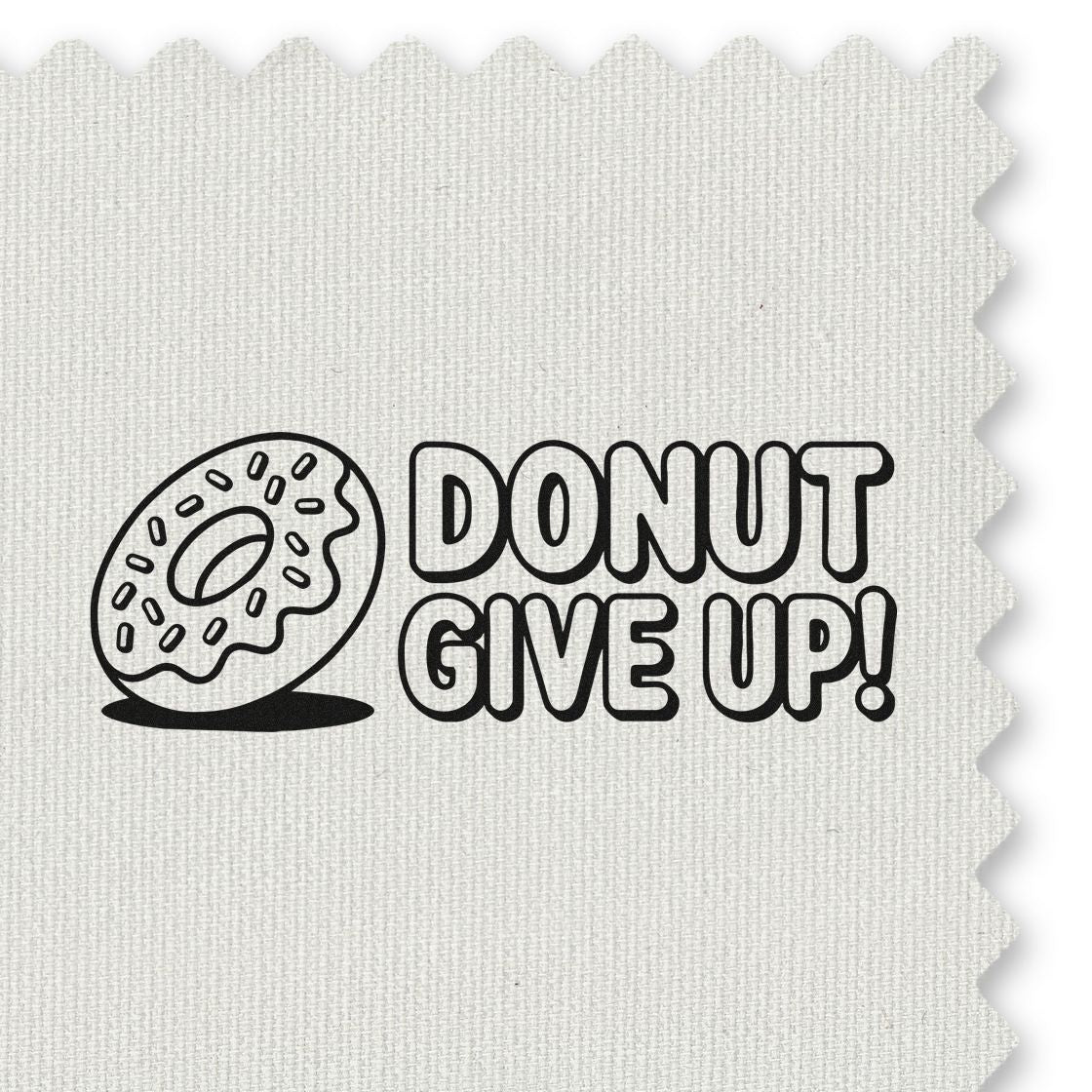 Black donut-themed stamp/seal on white fabric reading DONUT GIVE UP! with playful bakery design.