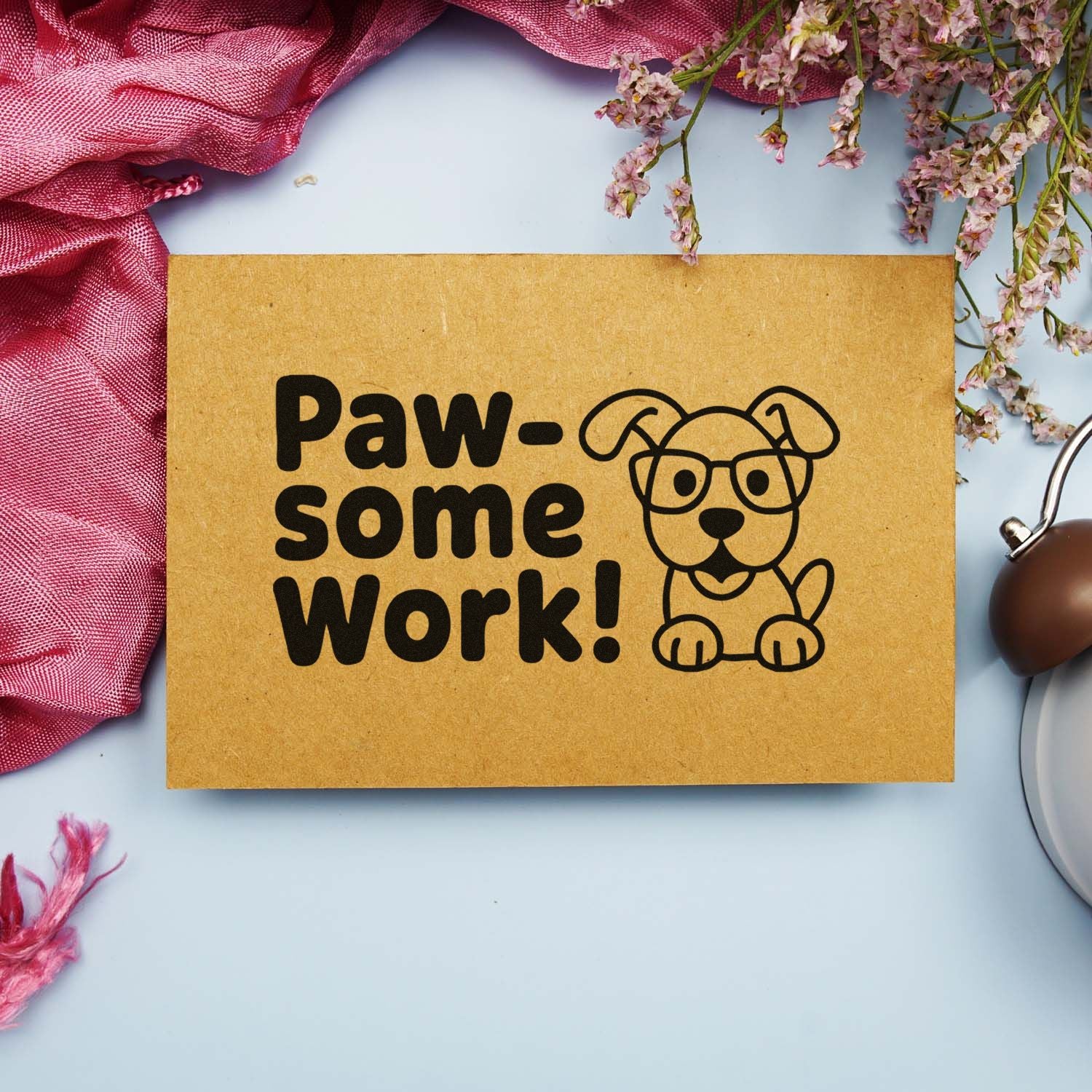 Kraft stamp and seal card with black Paw-some Work! text and dog graphic on light blue, framed by pink fabric and flowers.
