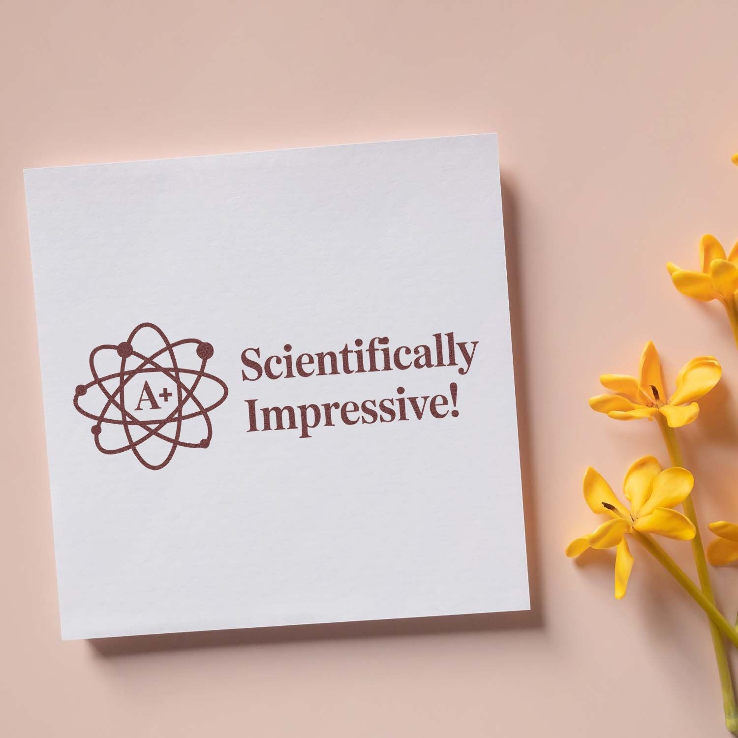 Brown science A+ stamp seal reading Scientifically Impressive! on white card, with yellow flowers on a peach background.