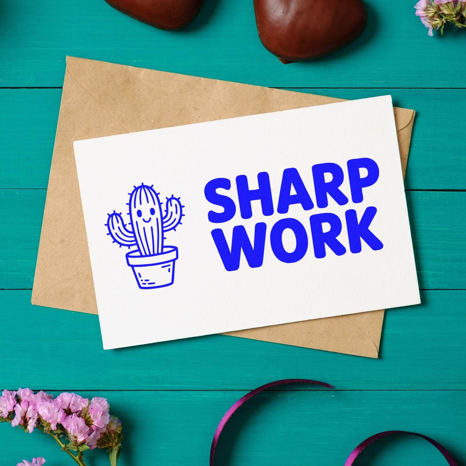 Blue cactus stamp and SHARP WORK seal on white card over a brown envelope on teal background